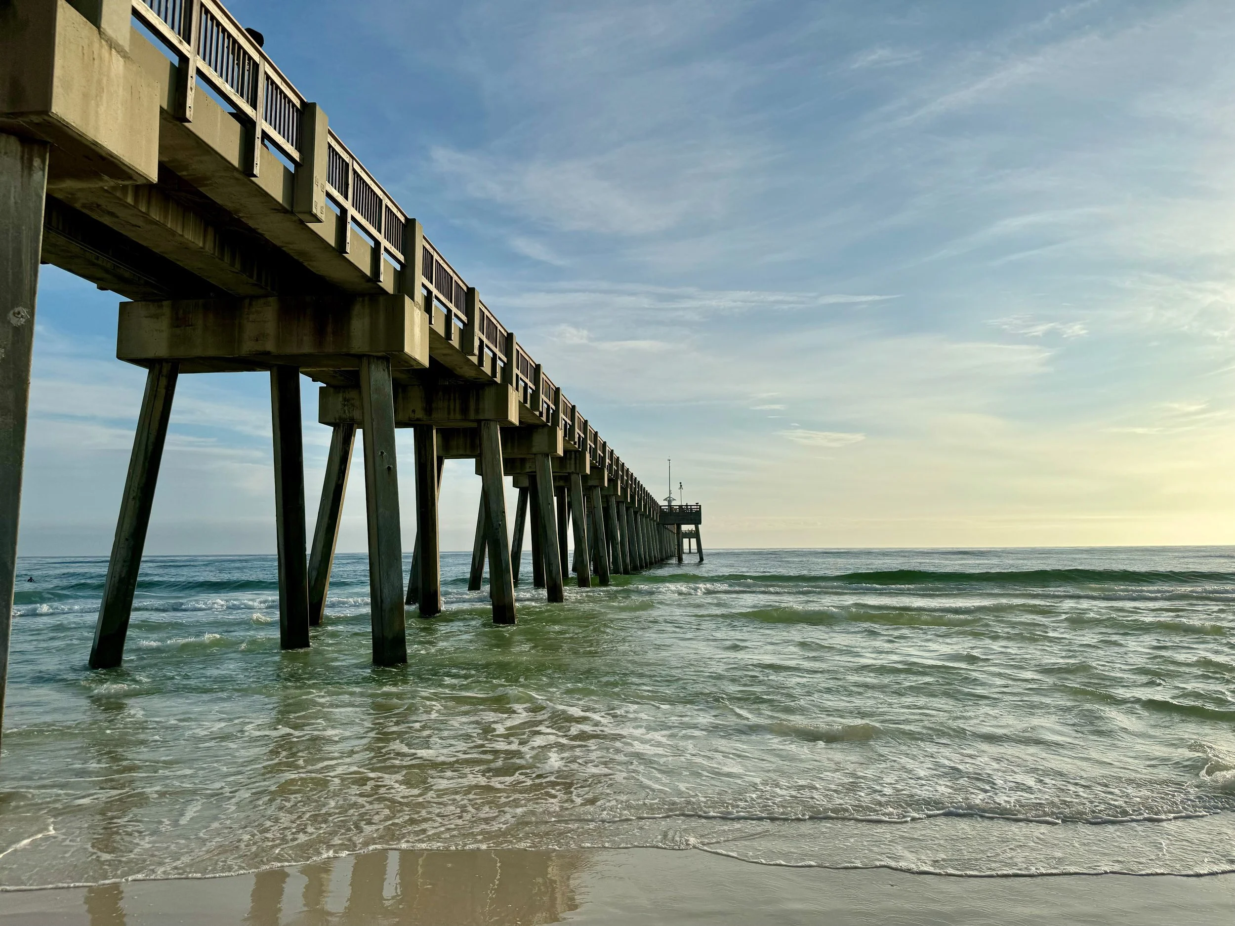 Ocean pier extending over water with clear sky