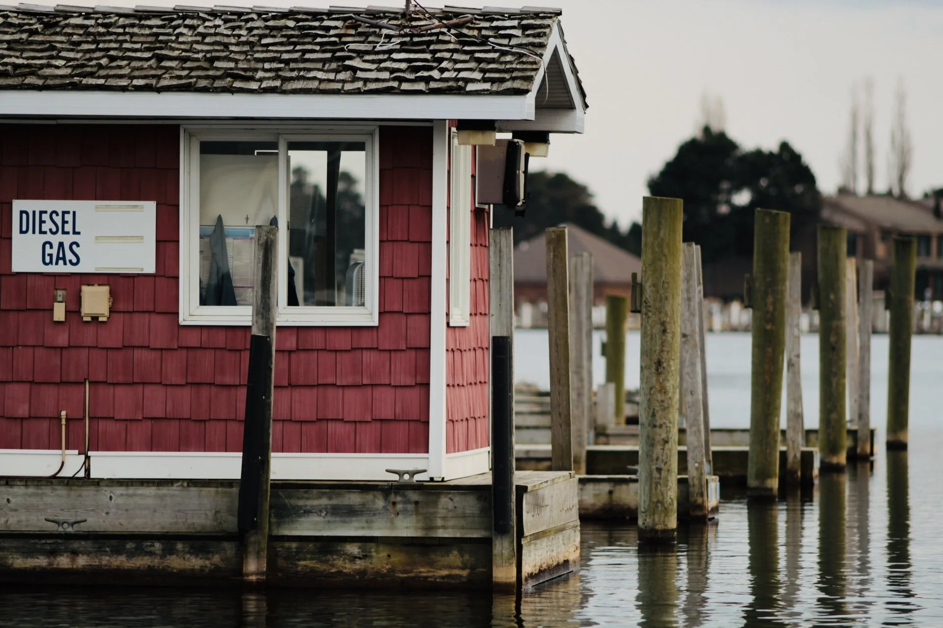 Red waterfront building with 'Diesel Gas' sign, wooden docks, and water in the foreground.