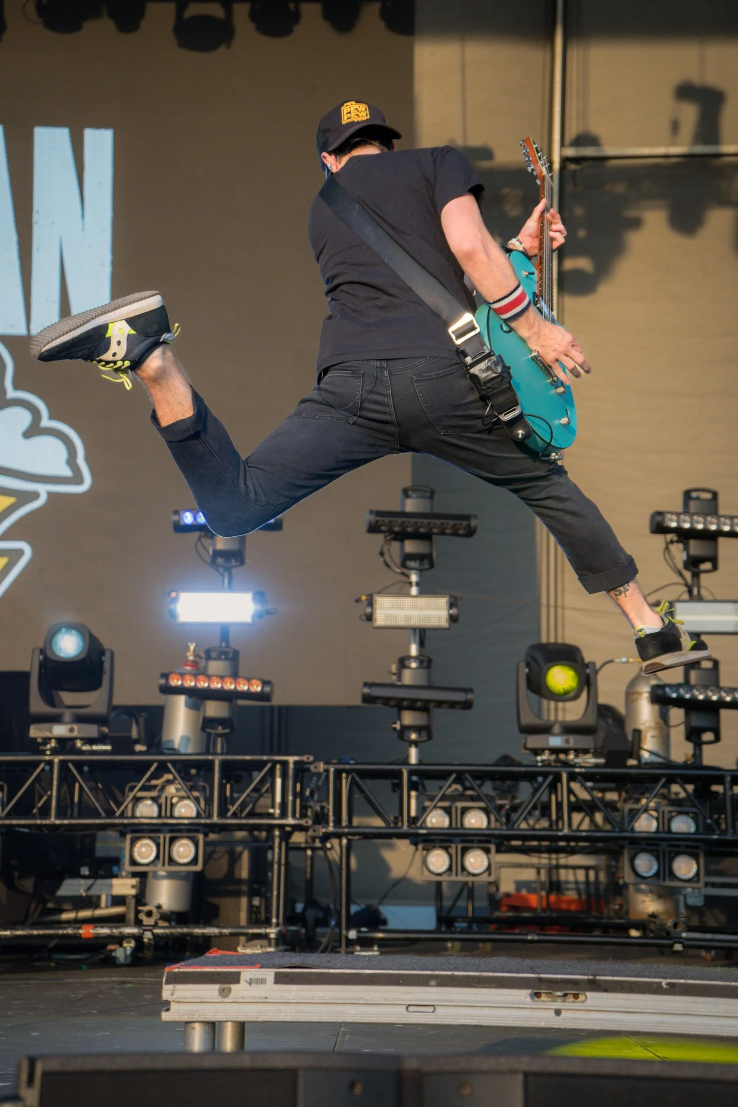 Musician jumping on stage holding a teal guitar