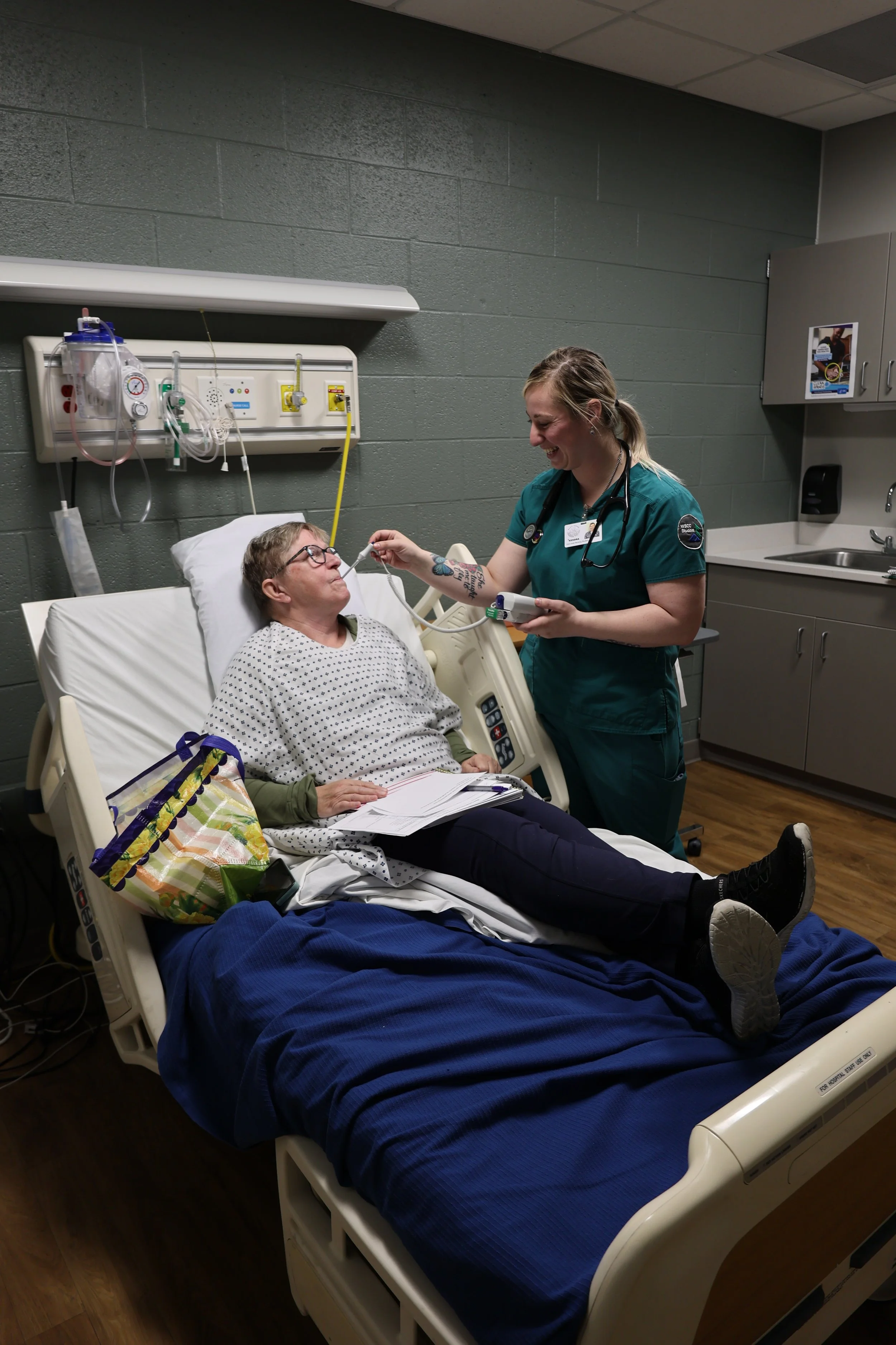 Nurse caring for a patient in a hospital bed; nurse taking patient's temperature with an oral thermometer.
