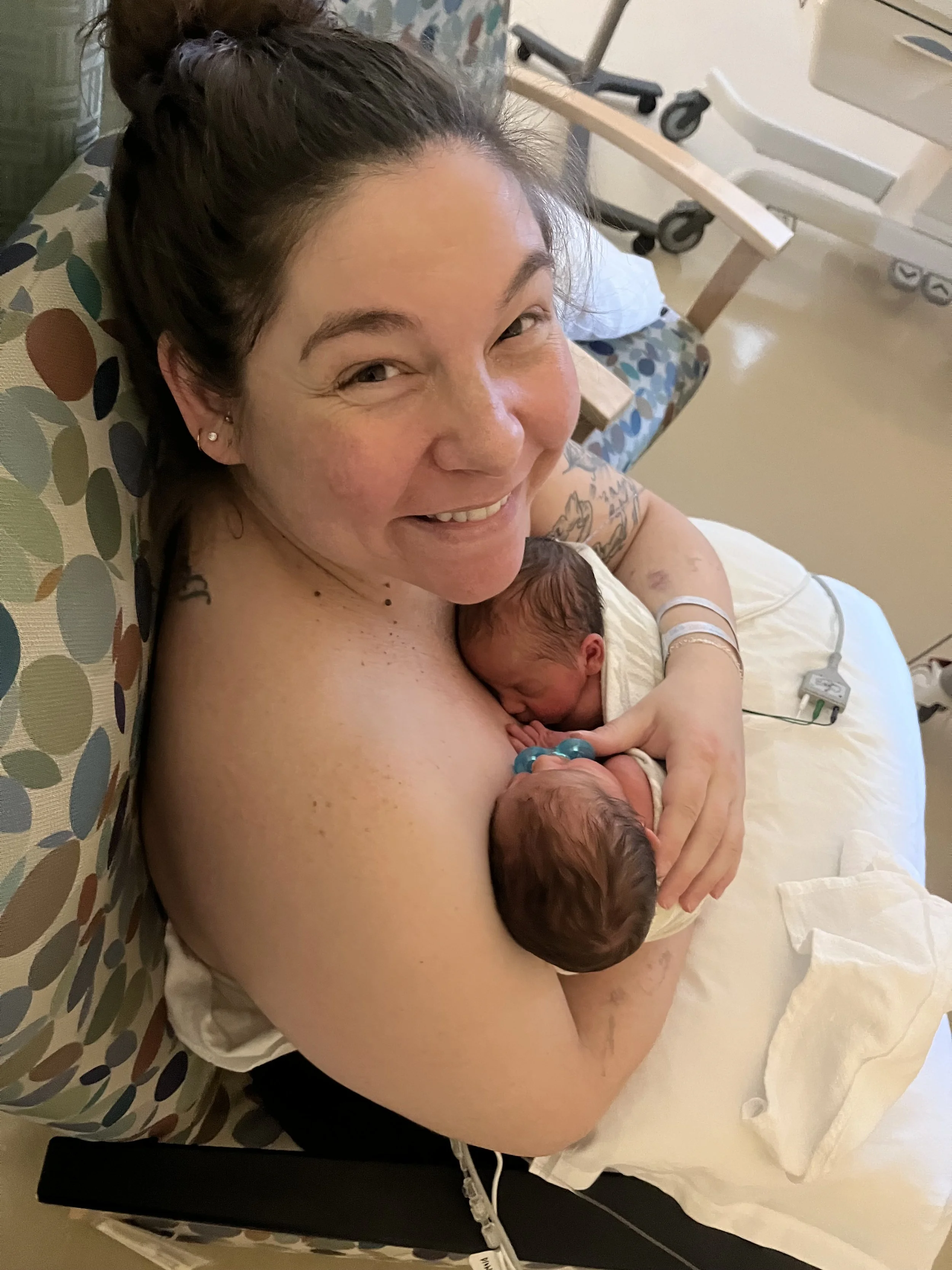 mom of preemie twins smiling with two babies on her chest