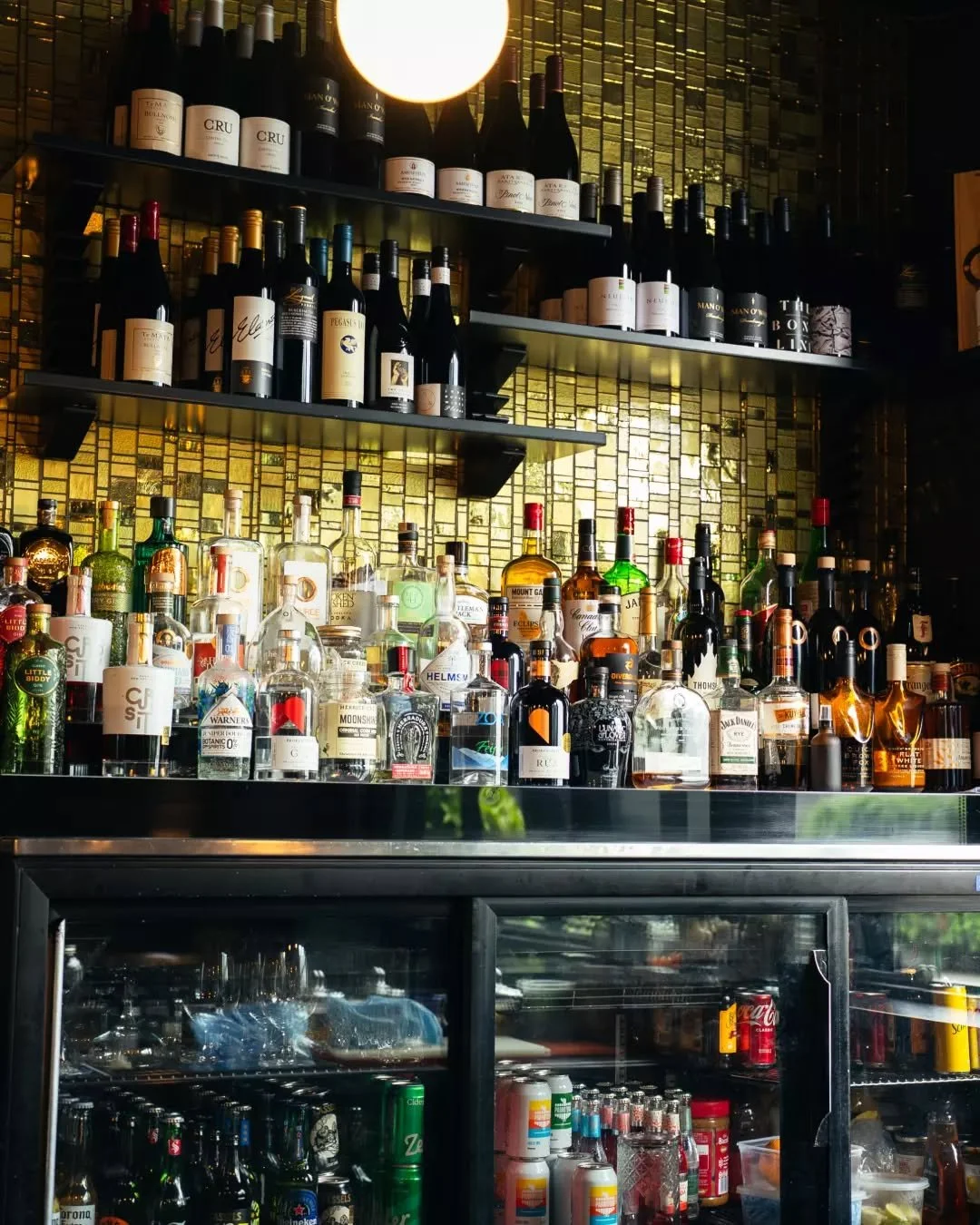 Curated for the connoisseur. Our back bar features a premier selection of global spirits and fine wines, set against our signature golden backdrop. Whether you seek a rare single malt or a crisp local vintage, every pour is a celebration of craftsman