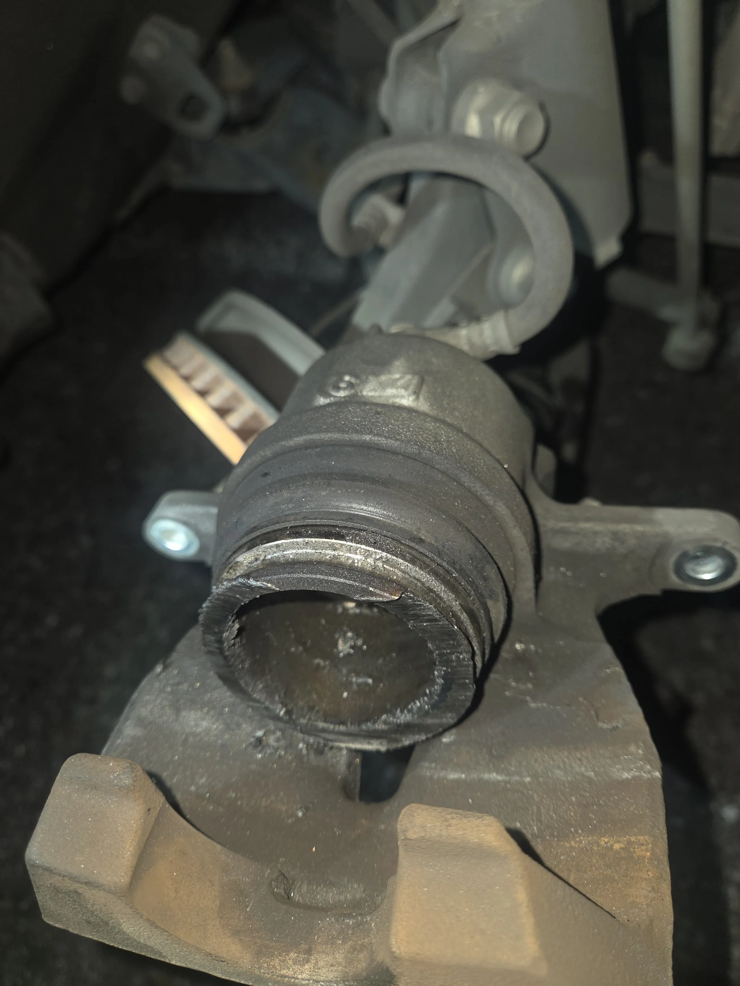 Close-up of a car's brake caliper and rotor assembly, showing the brake rotor missing from the assembly, revealing the central hub and mounting points.