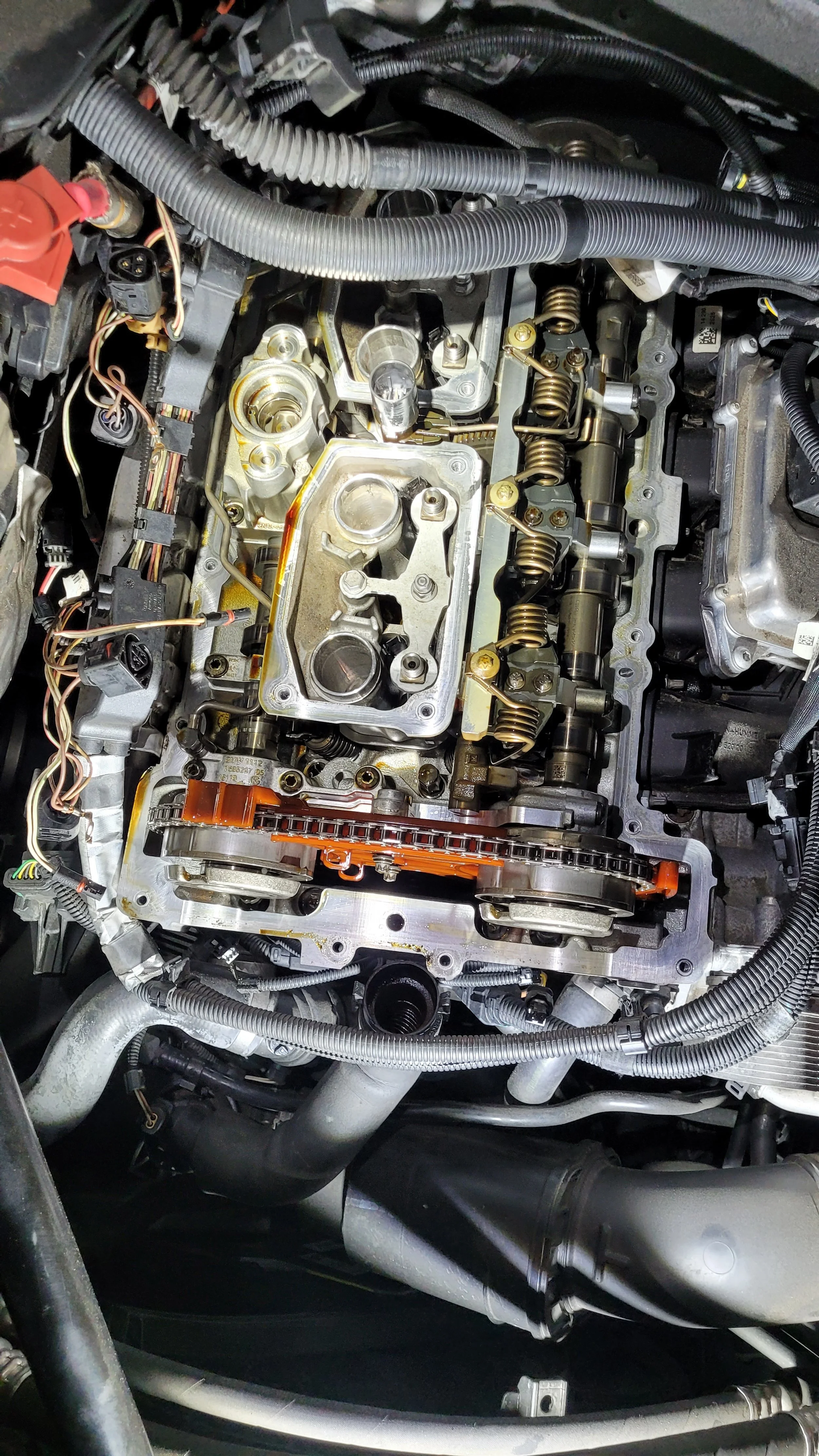 Close-up view of a car engine with the valve cover removed, exposing camshaft, valves, and timing chain components.