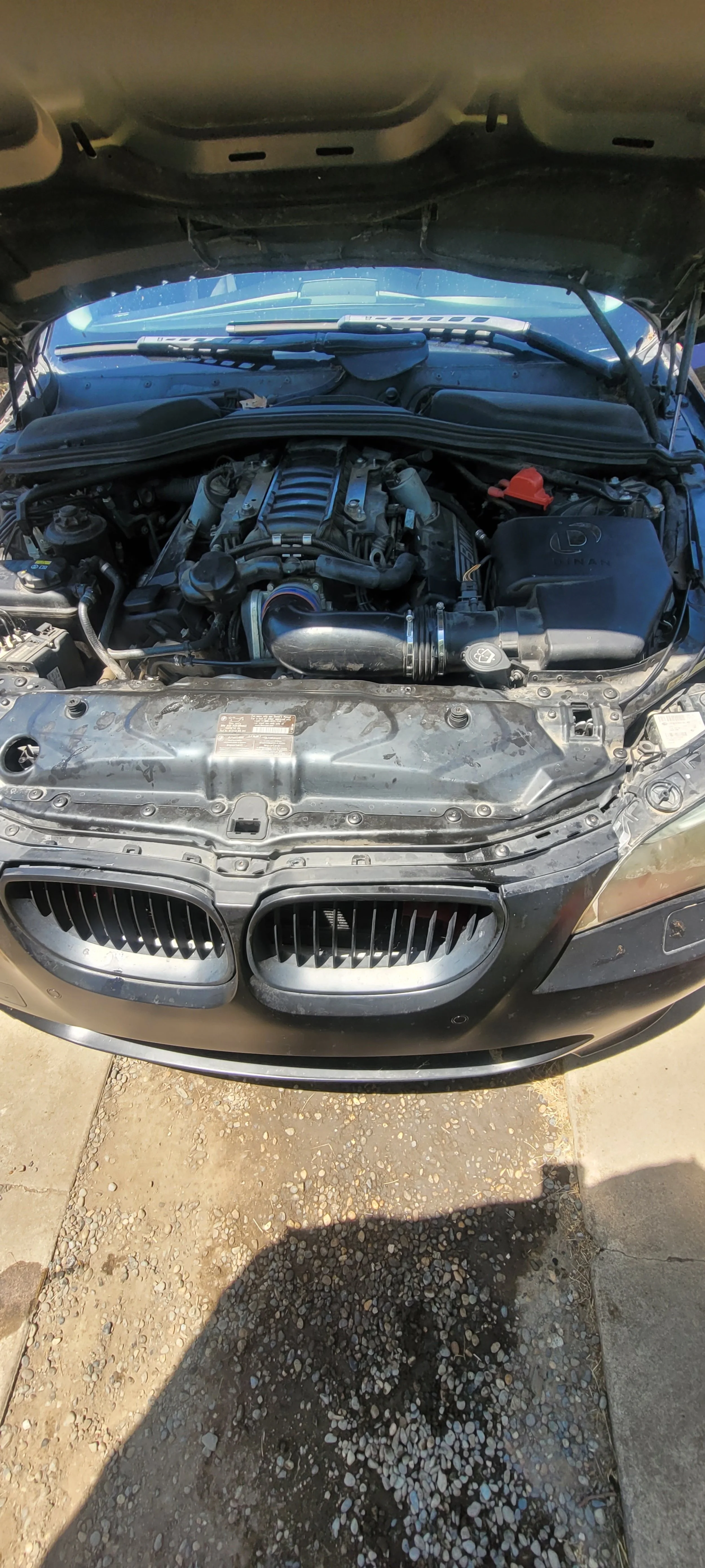A car with its hood open, showing the engine bay and front grille.