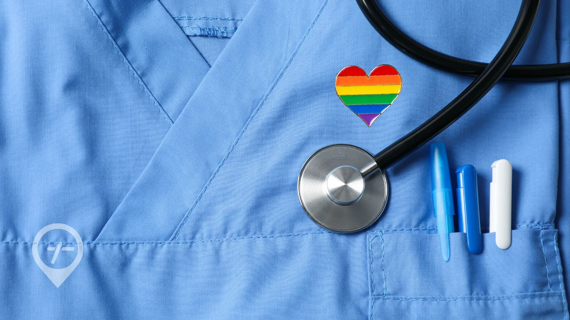 Blue scrubs form the backdrop to a rainbow heart pin