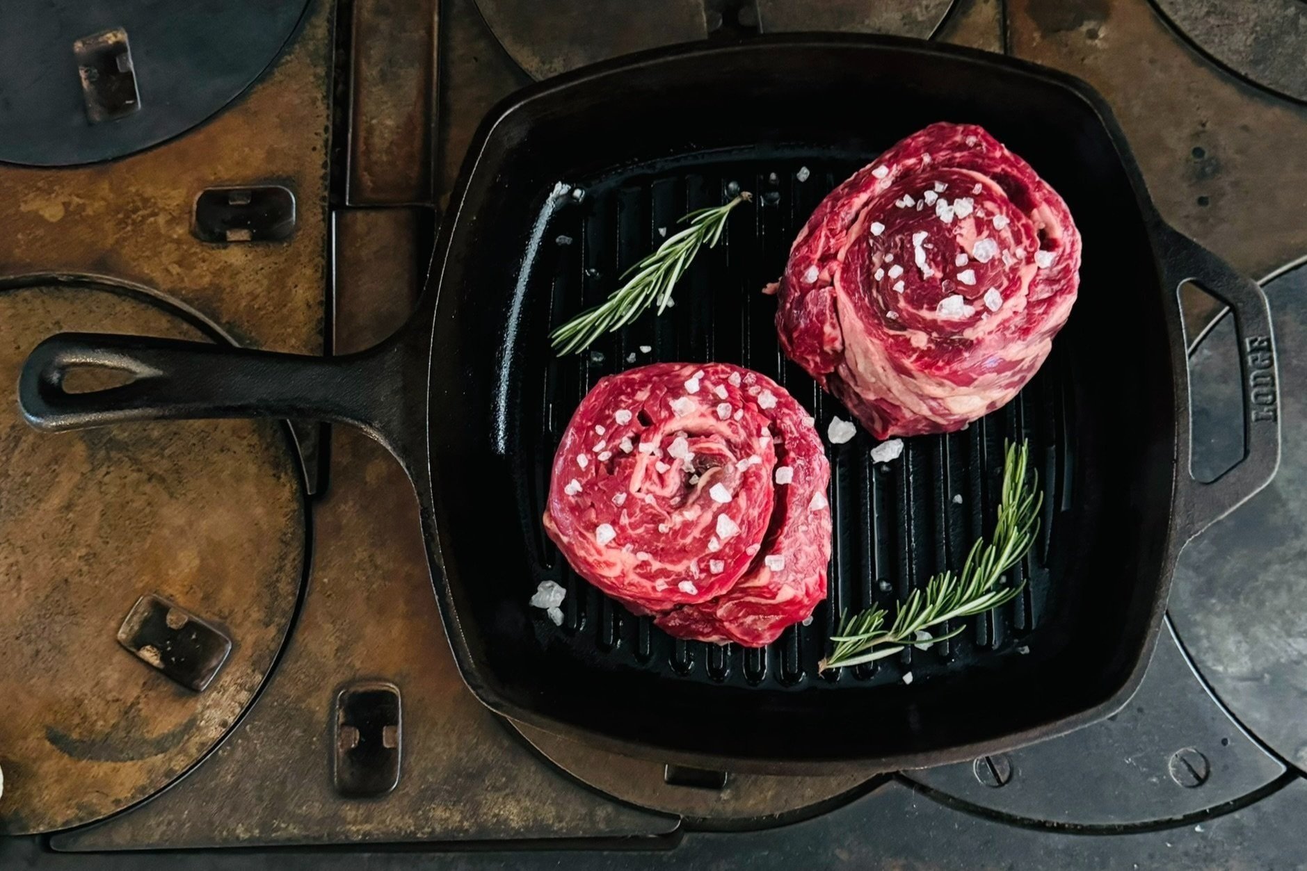 skirt steaks in cast iron pan with roasemary garnish.jpg