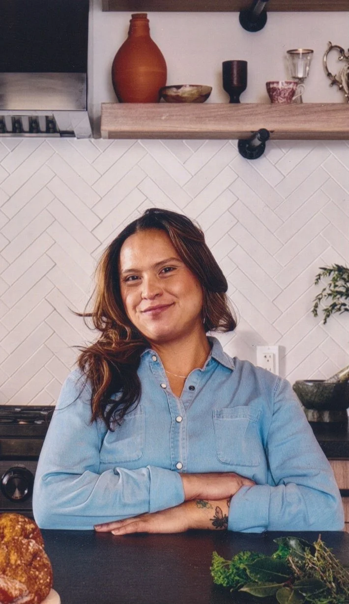 Daniela Swamp, Los Angeles food stylist and recipe author, smiling in a kitchen with plants and a tile backsplash.