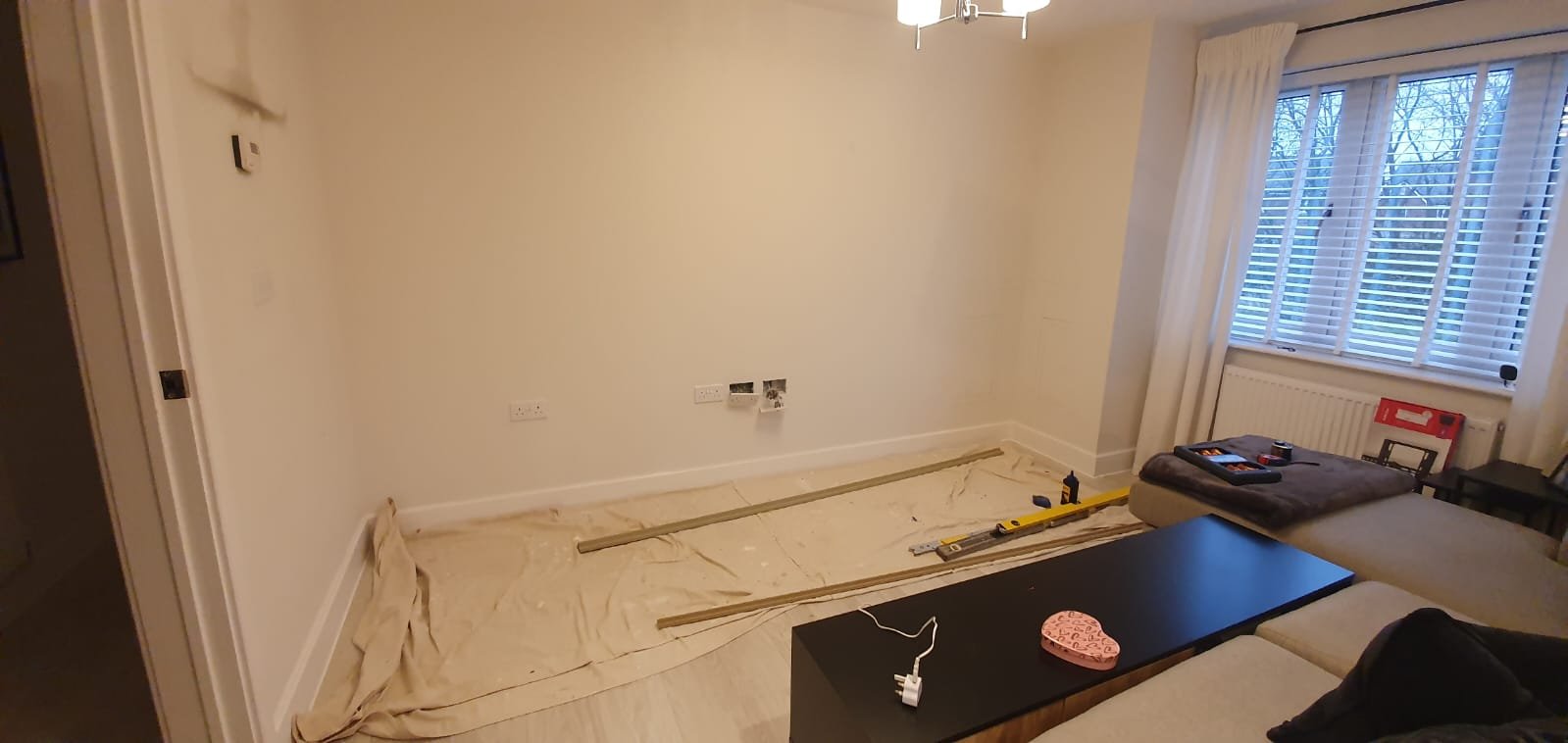 Living room interior with unadorned wall and tools on floor