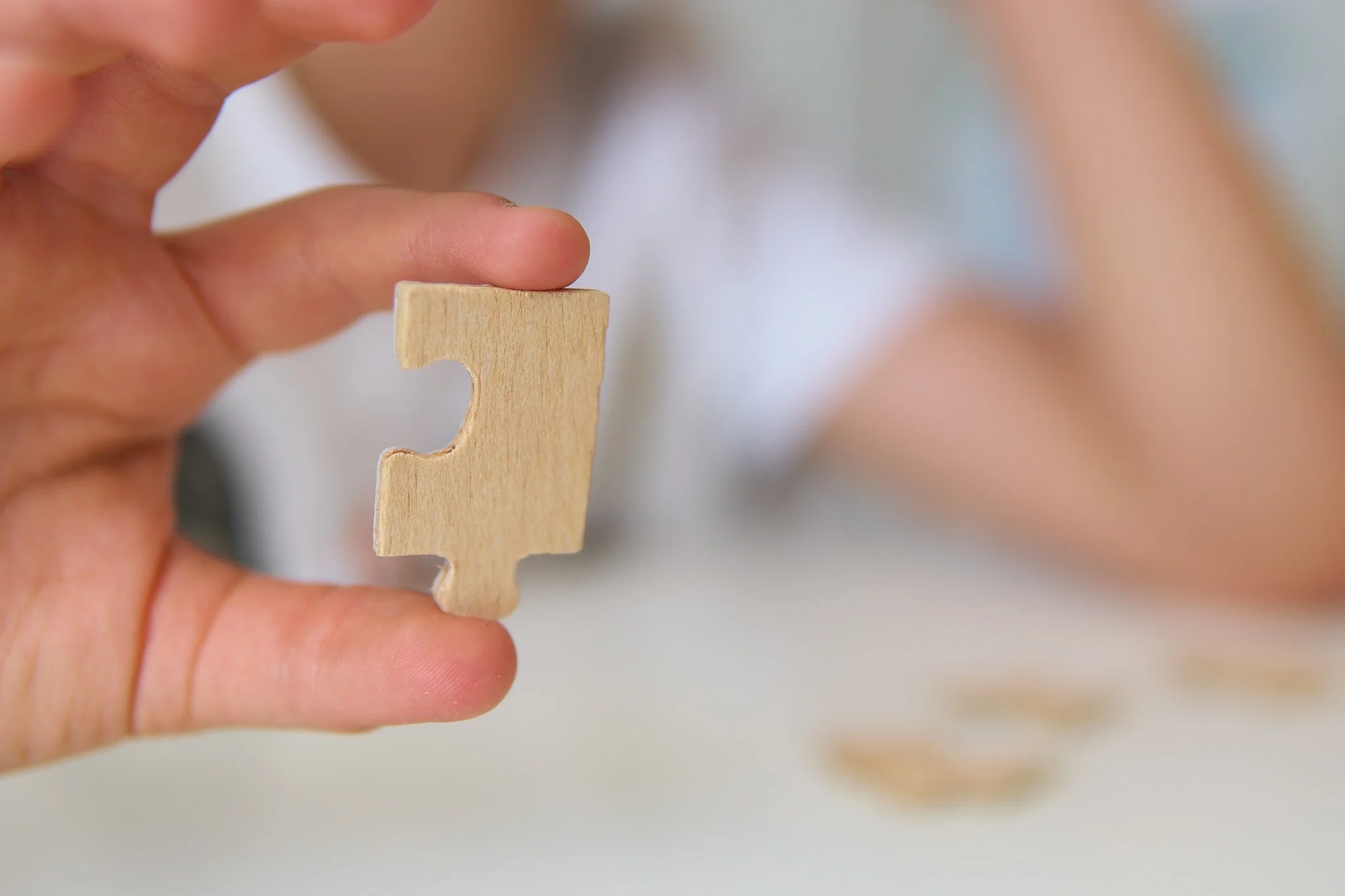 Pessoa segurando uma peça de quebra-cabeça de madeira