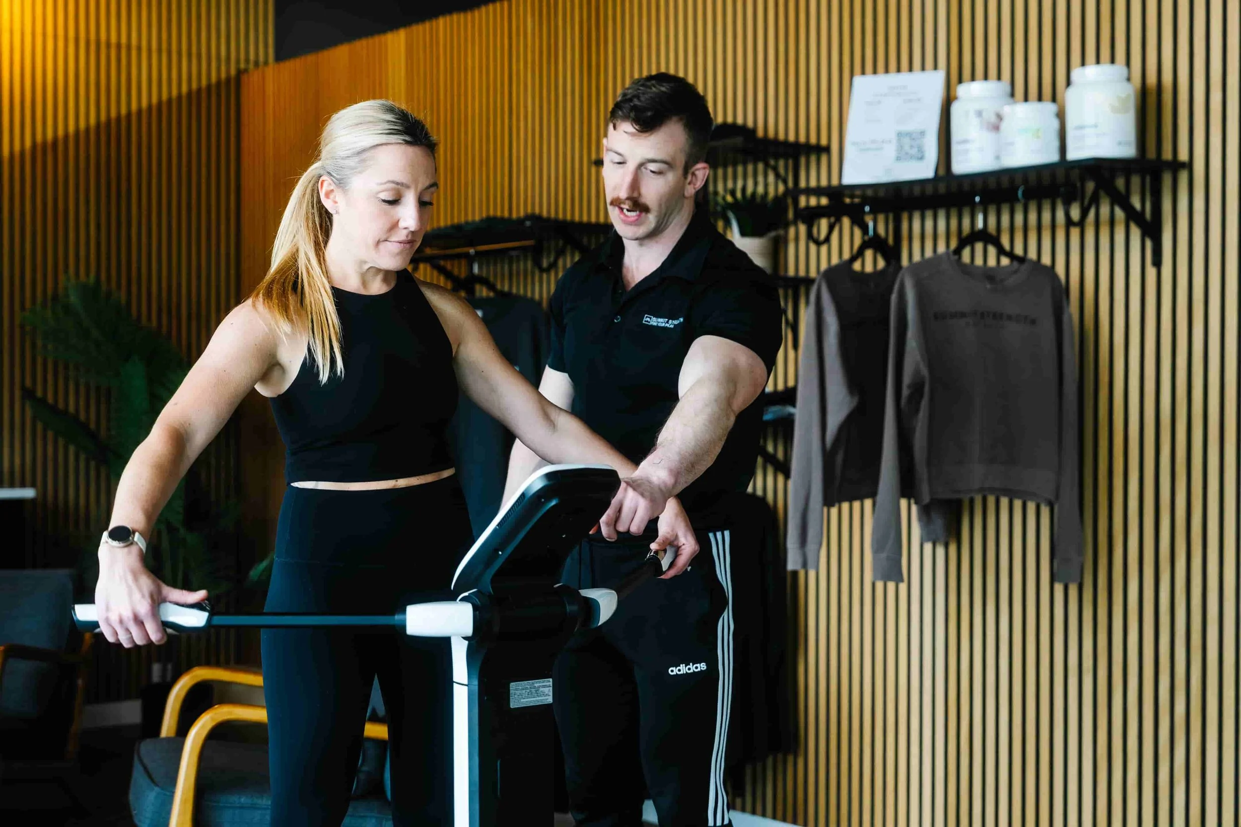 A male personal trainer adjusting settings on a body compostion machine for a female client at a boutique personal training gym in Milford, New Hampshire