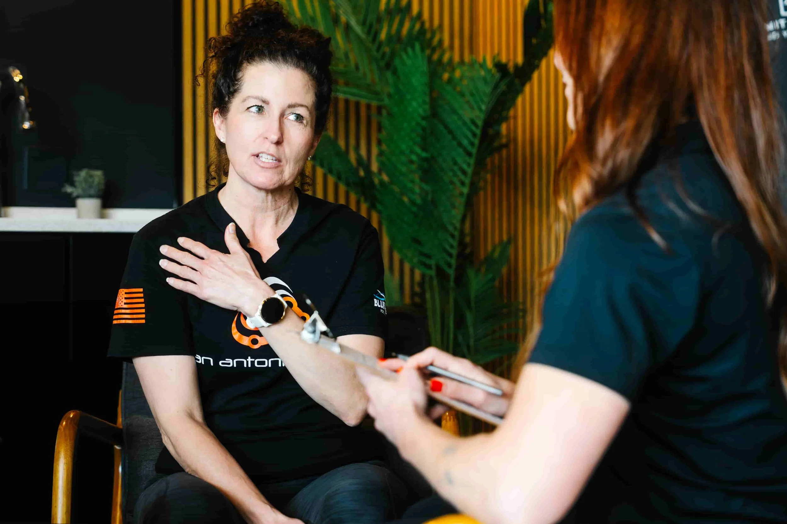 A female personal trainer speaking passionately with a new client during an initial fitness consultation at a boutique personal training studio in Milford, New Hampshire