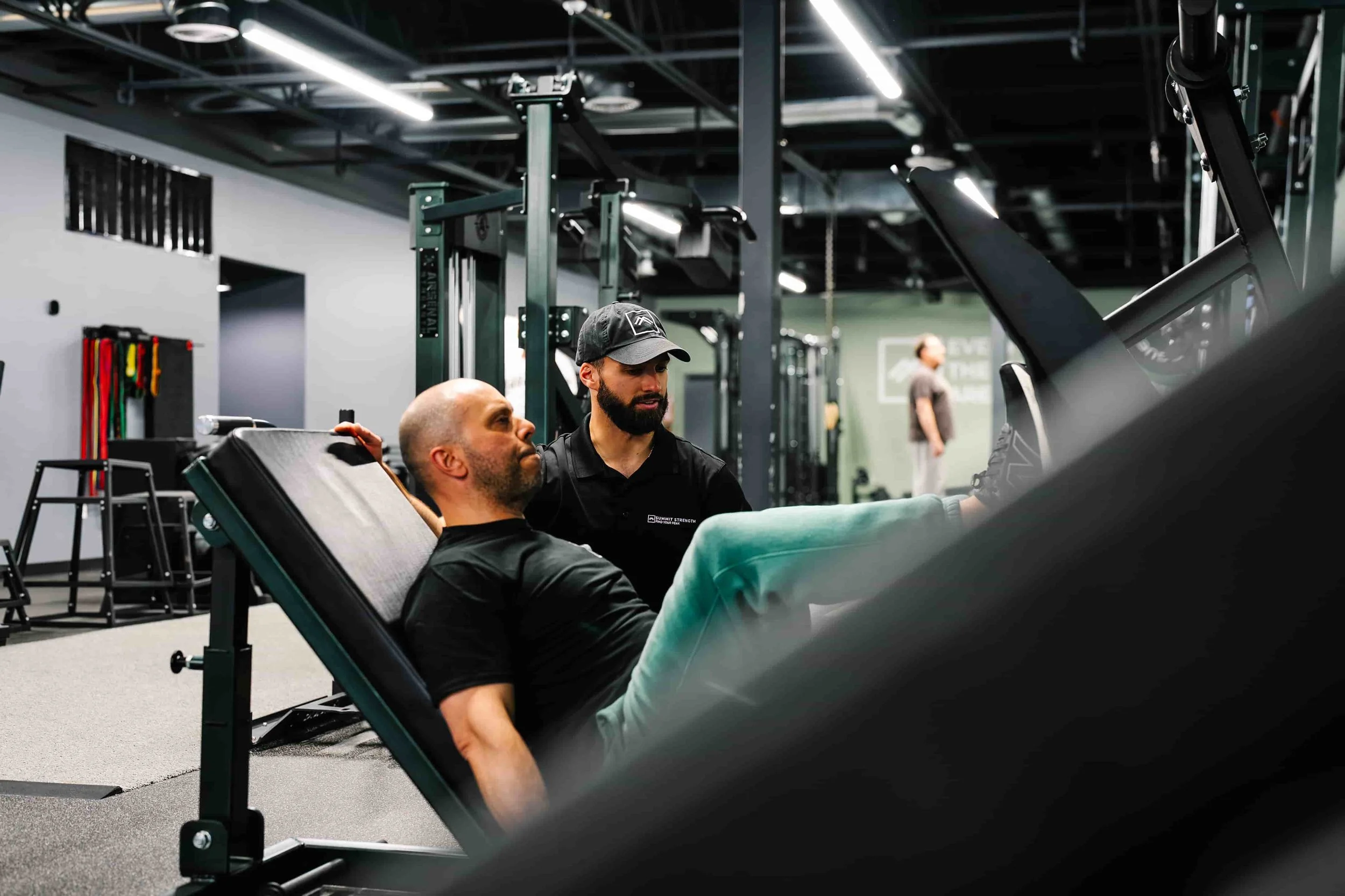 Personal trainer coaching a client through a leg press exercise at Summit Strength gym in New Hampshire