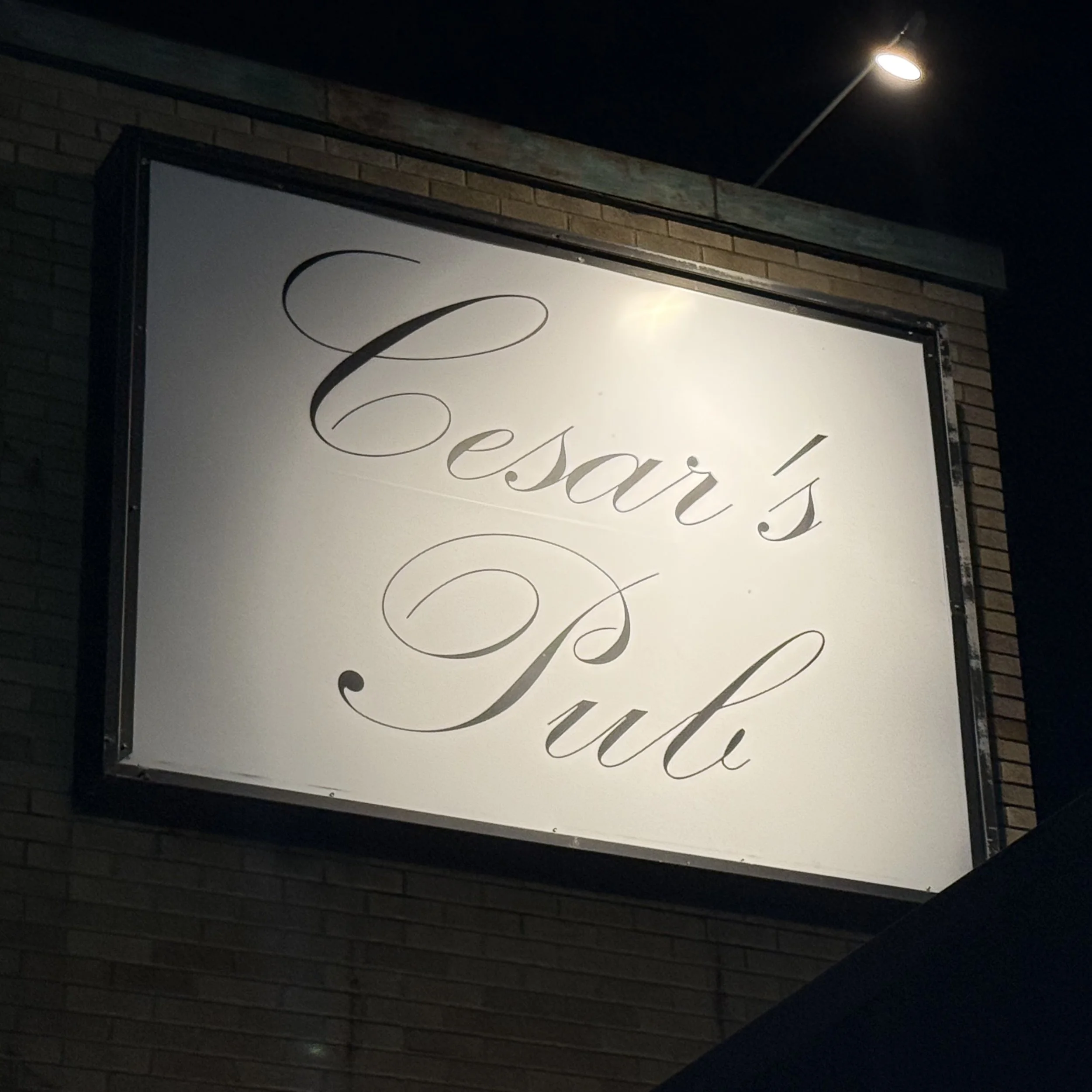 Illuminated Cesar’s Pub exterior sign above the building in Standale, Grand Rapids, Michigan, a local karaoke venue featured in the GRkaraoke.com Karaoke Marathon 2026
