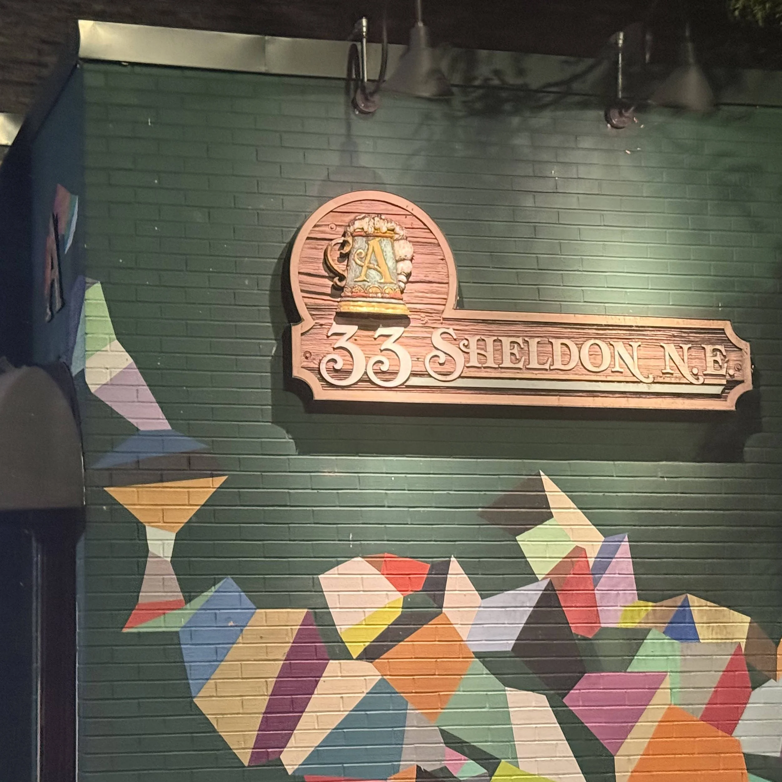 33 Sheldon Ave NE wall sign and colorful mural outside The Apartment Lounge, a downtown Grand Rapids bar and karaoke venue featured in the GRkaraoke.com Karaoke Marathon 2026
