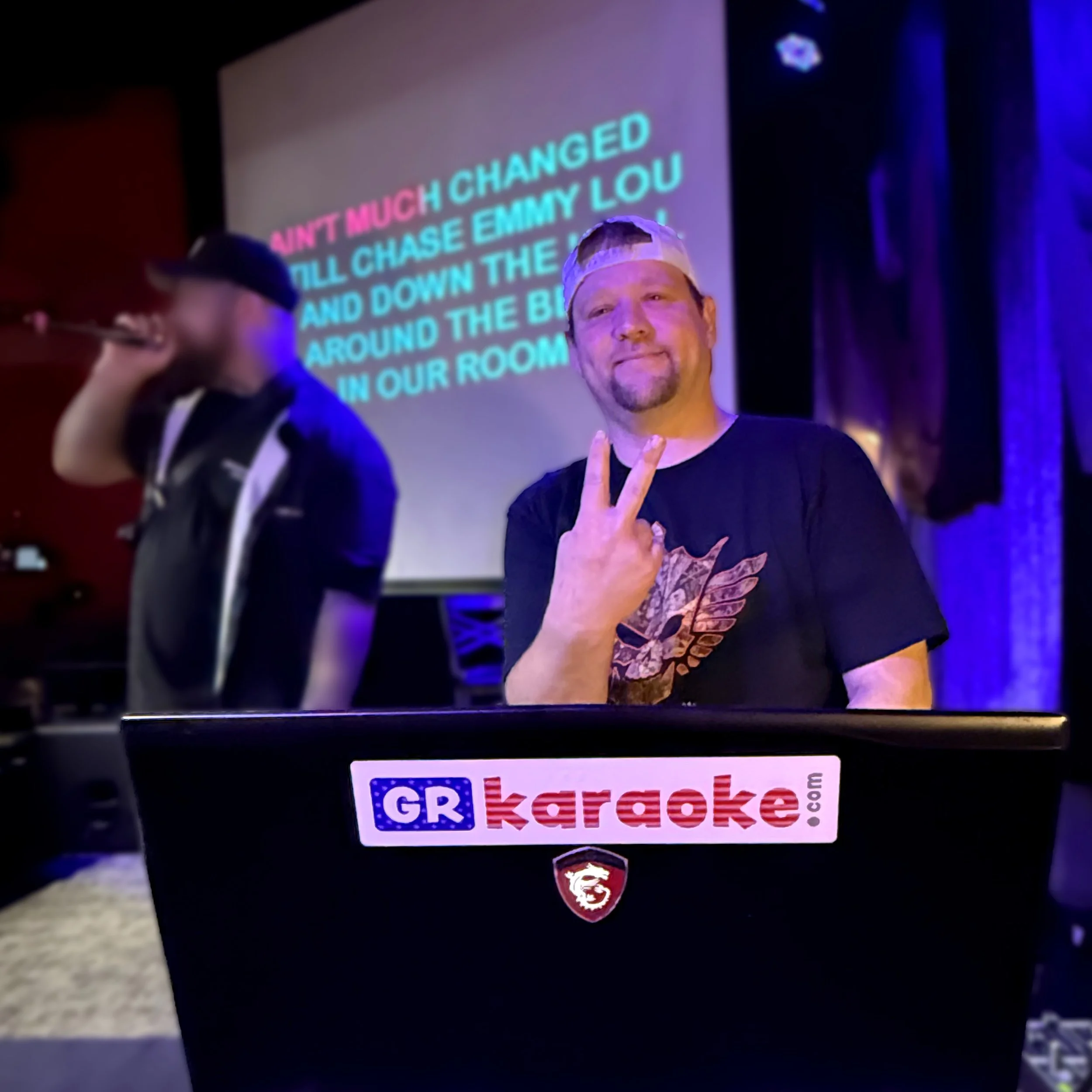 Karaoke host Brian C. at Firebird Bar GR in Grand Rapids, Michigan, behind the booth with a GRkaraoke.com sticker during the final stop of the Karaoke Marathon 2026