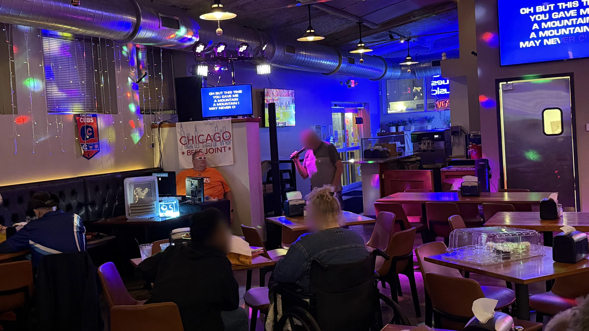 Karaoke night inside Chicago Beef Joint in Grand Rapids, Michigan, with dining tables, colorful stage lighting and karaoke lyric screens during the GRkaraoke.com Karaoke Marathon 2026