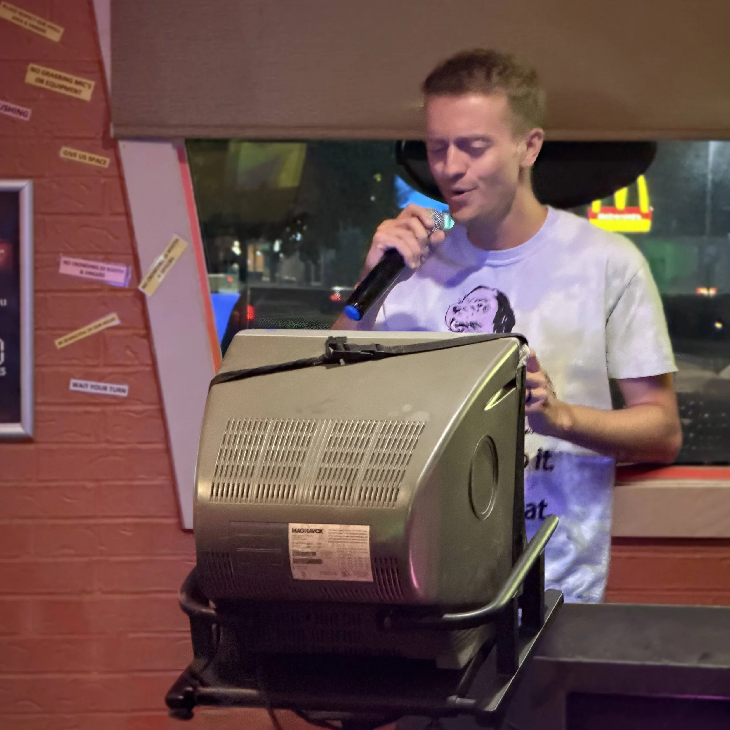 GRkaraoke.com founder Chris singing karaoke at Play Station Pub on Leonard Street in Grand Rapids, Michigan, using the venue’s classic CRT lyric monitor during the Karaoke Marathon 2026