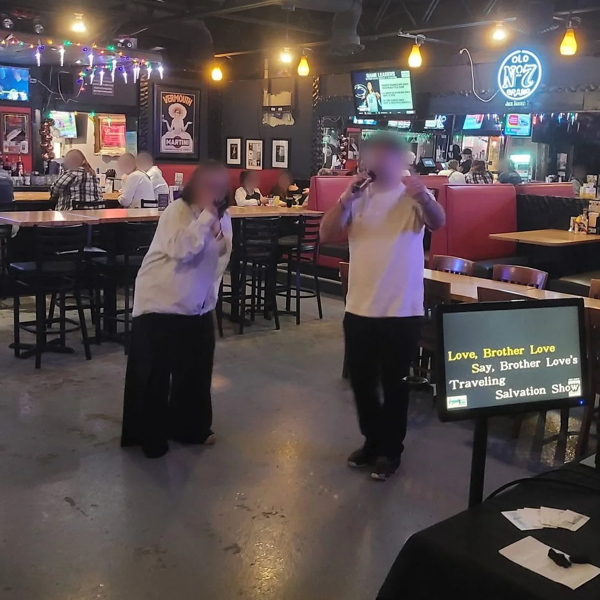 Two singers performing a karaoke duet at Cesar’s Pub in Standale, Grand Rapids, Michigan, with the bar and dining area in the background during the GRkaraoke.com Karaoke Marathon 2026