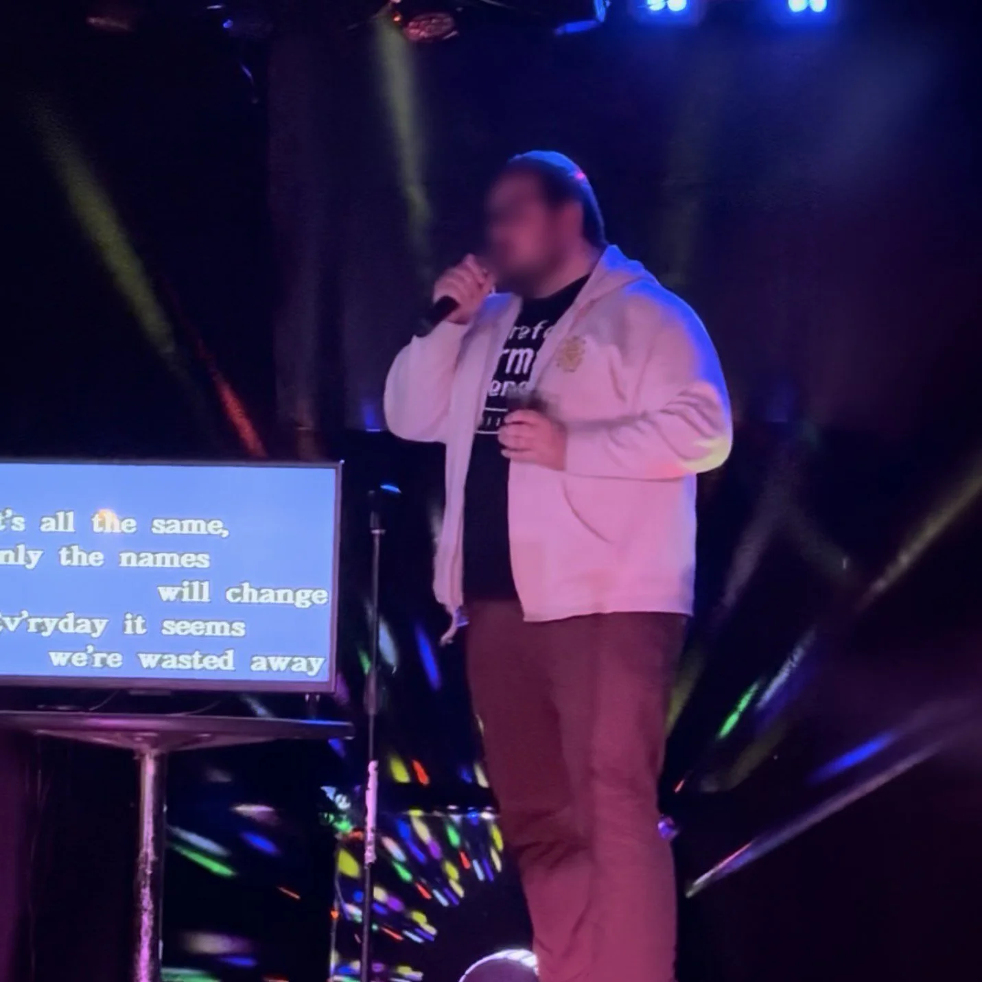 Singer performing karaoke at Twisted Bull Saloon in Grand Rapids, Michigan, with colorful stage lighting and karaoke lyrics during the GRkaraoke.com Karaoke Marathon 2026