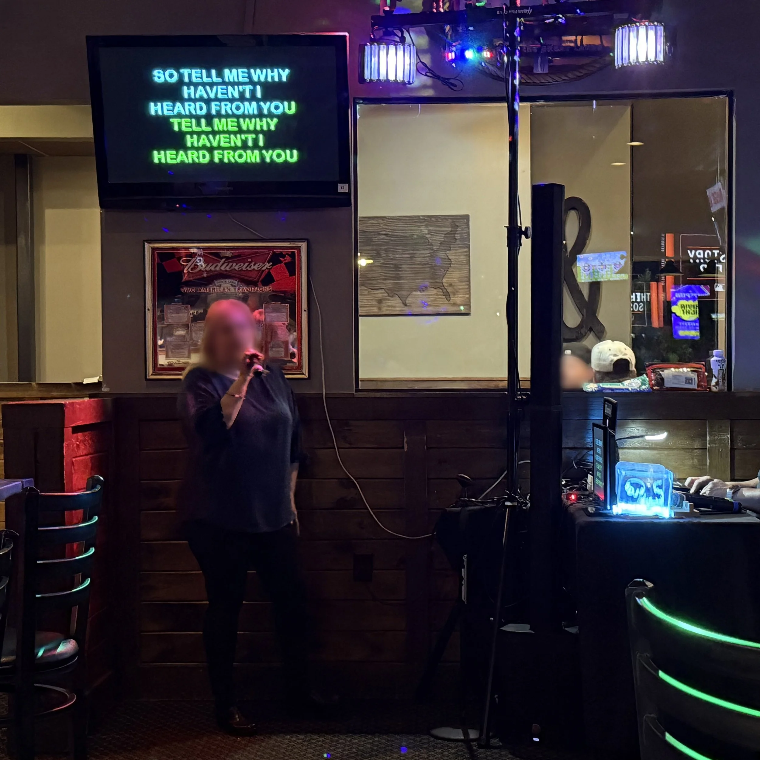 Singer performing karaoke at Main St. Pub in Allendale, Michigan, with karaoke lyrics displayed on screen during the GRkaraoke.com Grand Rapids Karaoke Marathon 2026