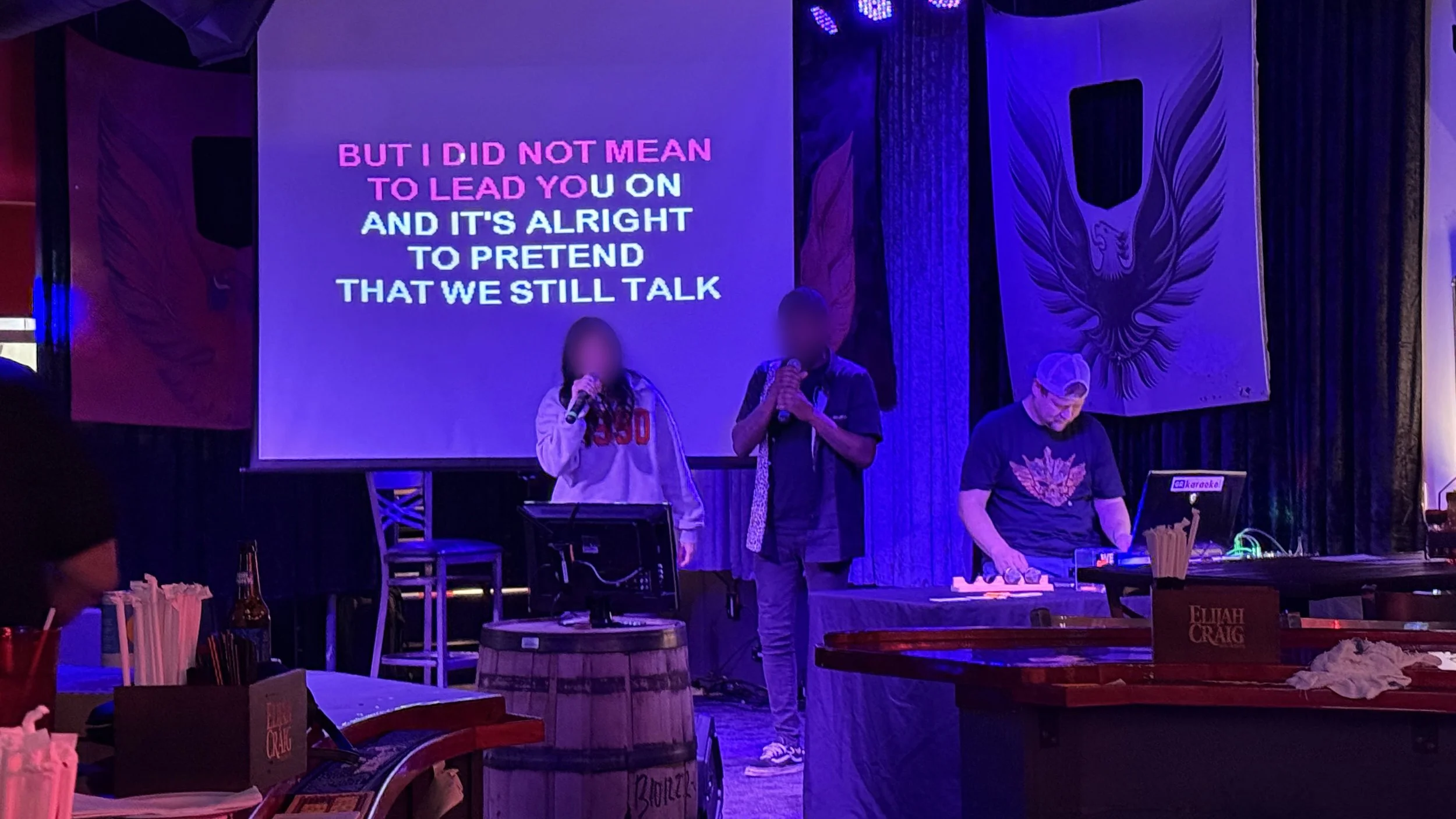 Two singers performing karaoke at Firebird Bar GR in Grand Rapids, Michigan, with karaoke host Brian C., projected lyrics and colorful stage lighting during the final stop of the GRkaraoke.com Karaoke Marathon 2026