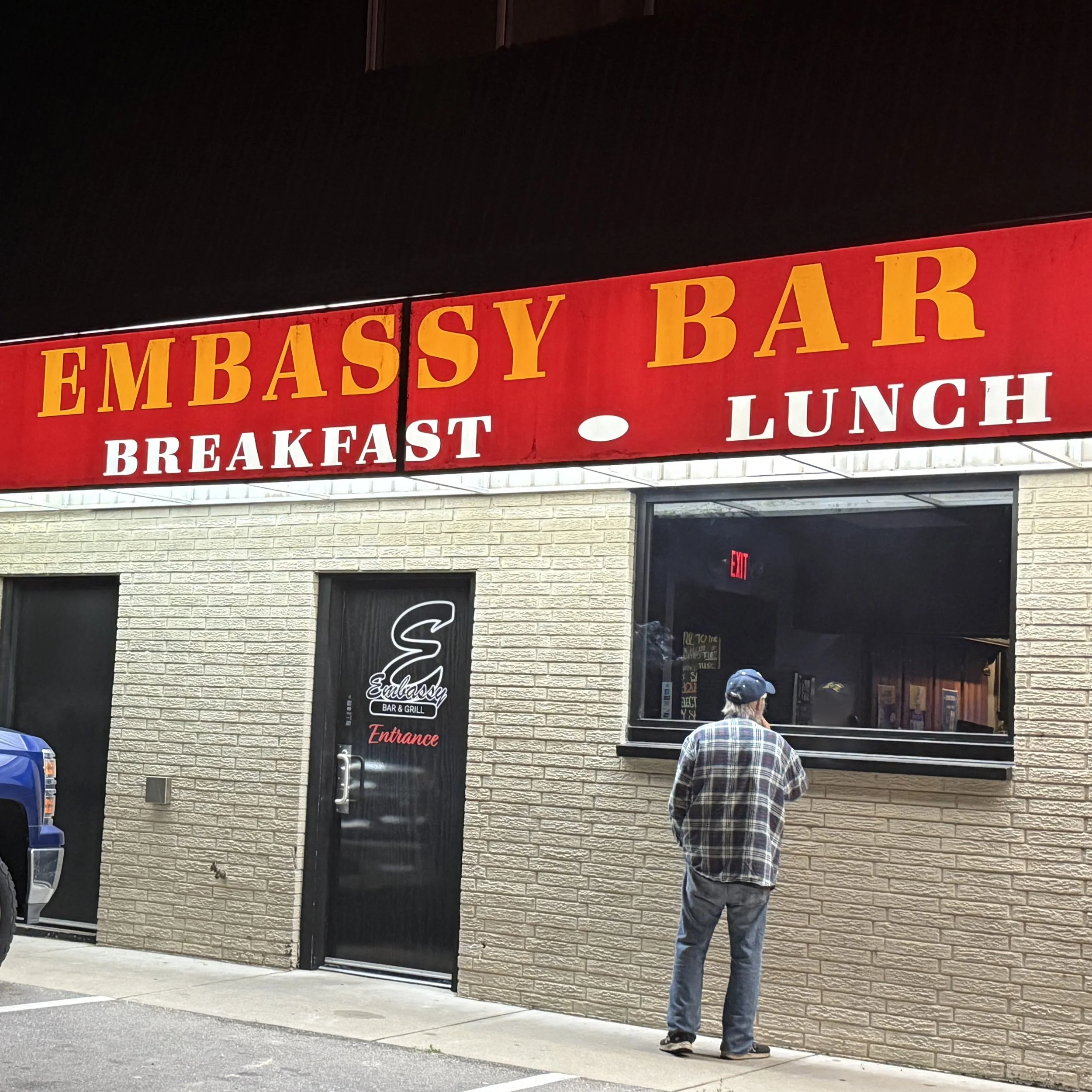 Exterior of Embassy Bar & Grill in West Olive, Michigan, showing the entrance and Embassy Bar breakfast and lunch sign during the GRkaraoke.com Karaoke Marathon 2026