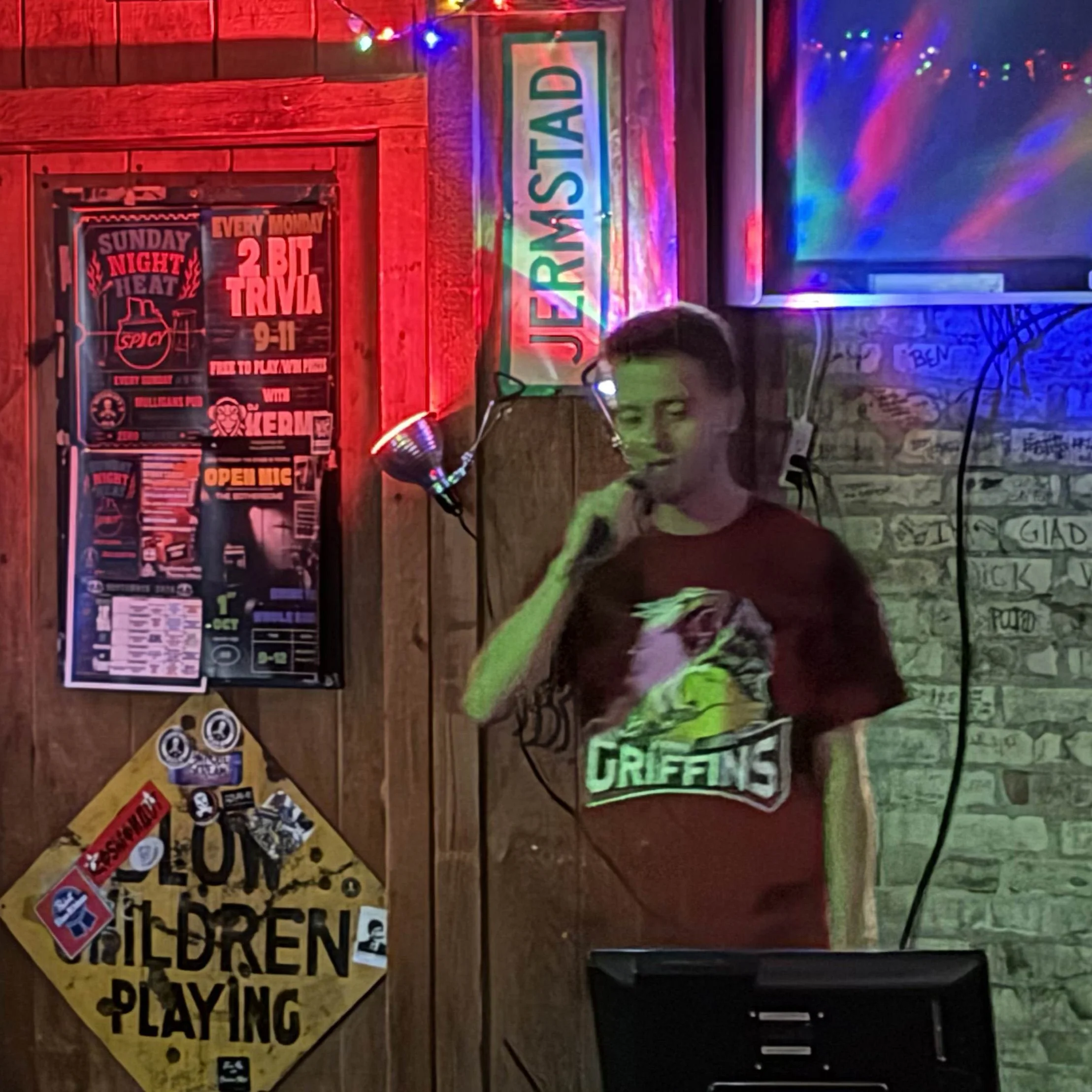 GRkaraoke.com founder Chris singing karaoke at Mulligan’s Pub in Eastown Grand Rapids, Michigan, with colorful bar lighting during the Karaoke Marathon 2026
