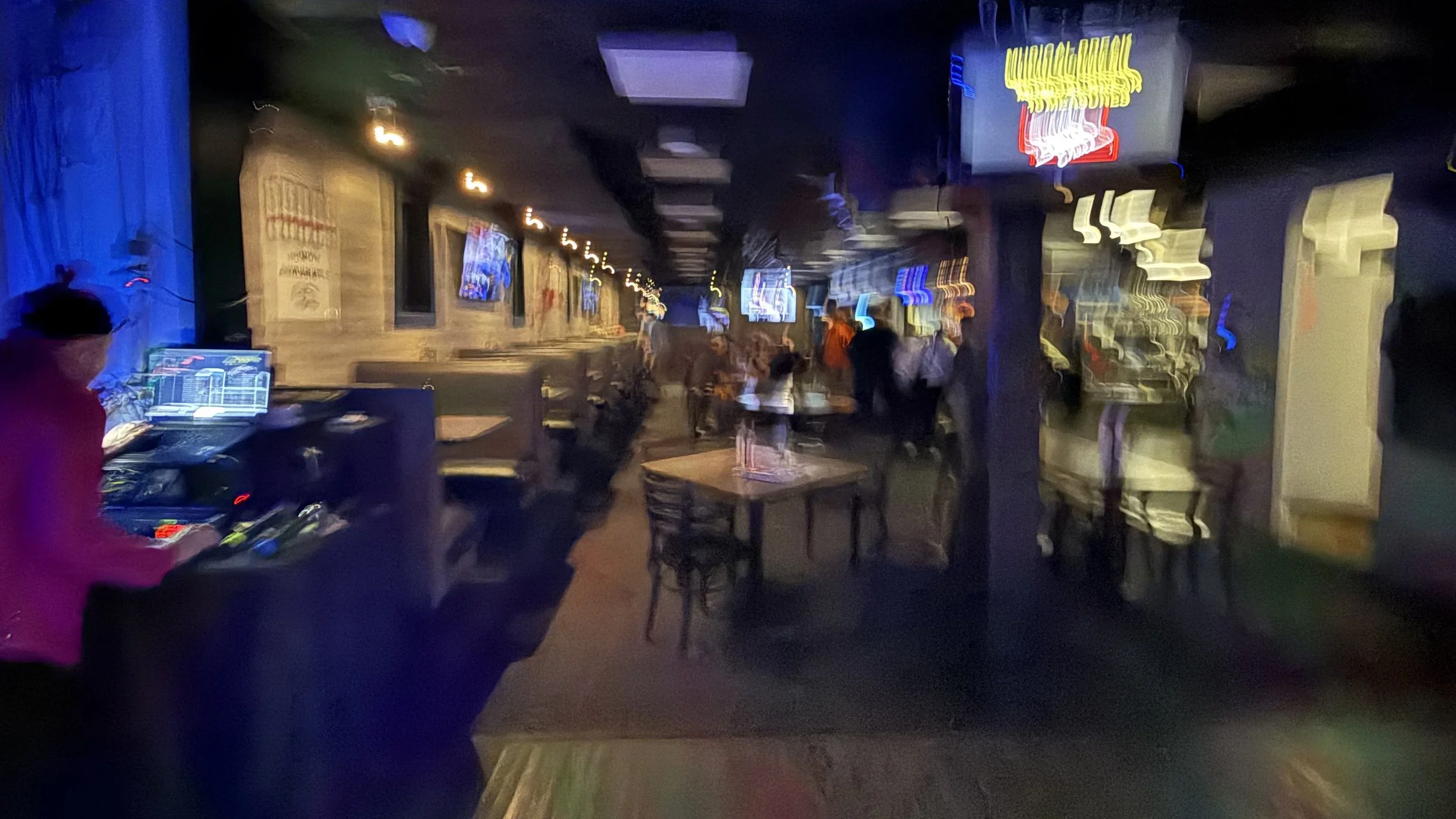 Blurry view from the karaoke stage at Embassy Bar & Grill in West Olive, Michigan, showing the bar, tables and crowd during the GRkaraoke.com Karaoke Marathon 2026