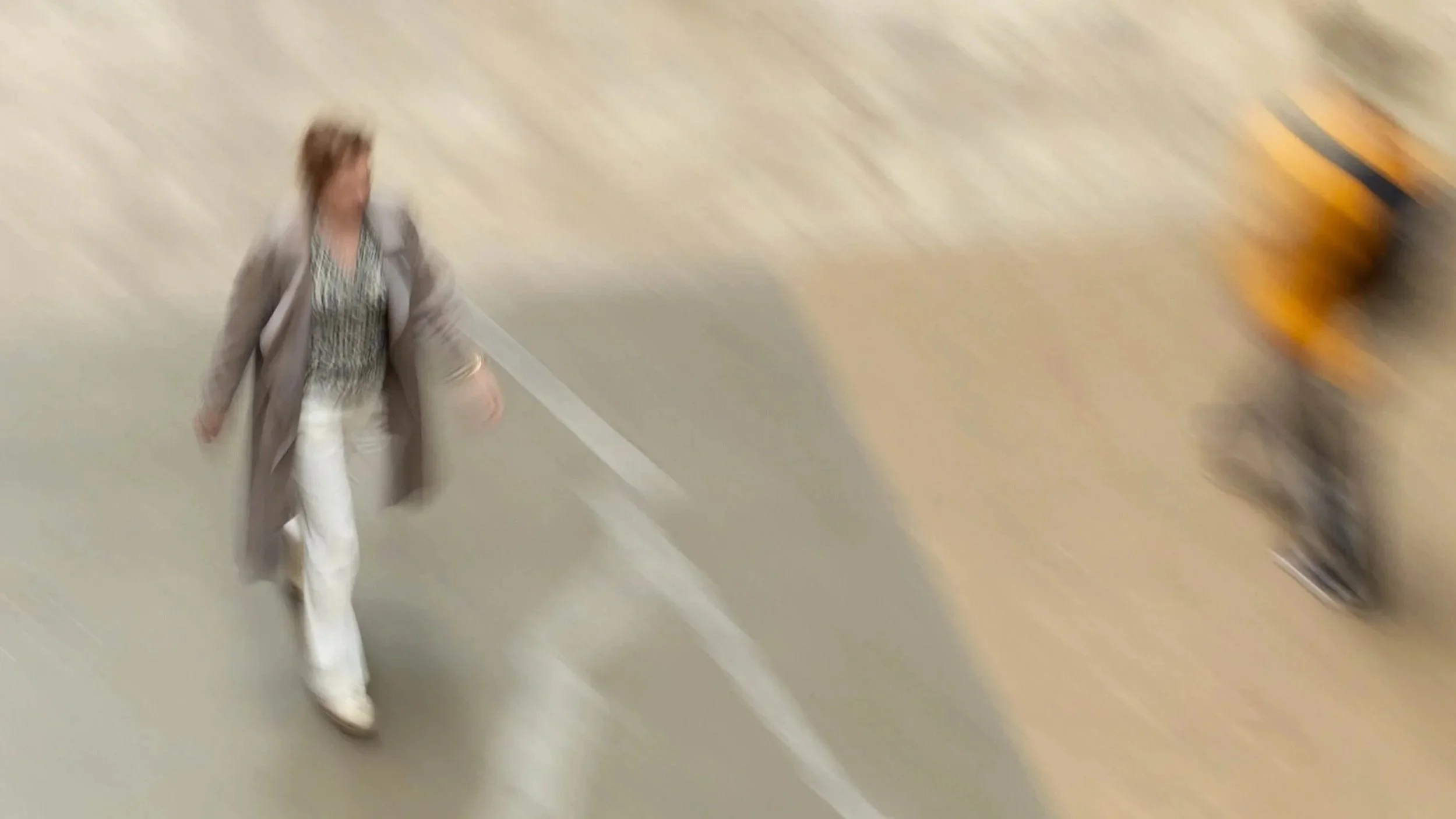 A woman walking in a parking garage with a yellow vehicle in the background.