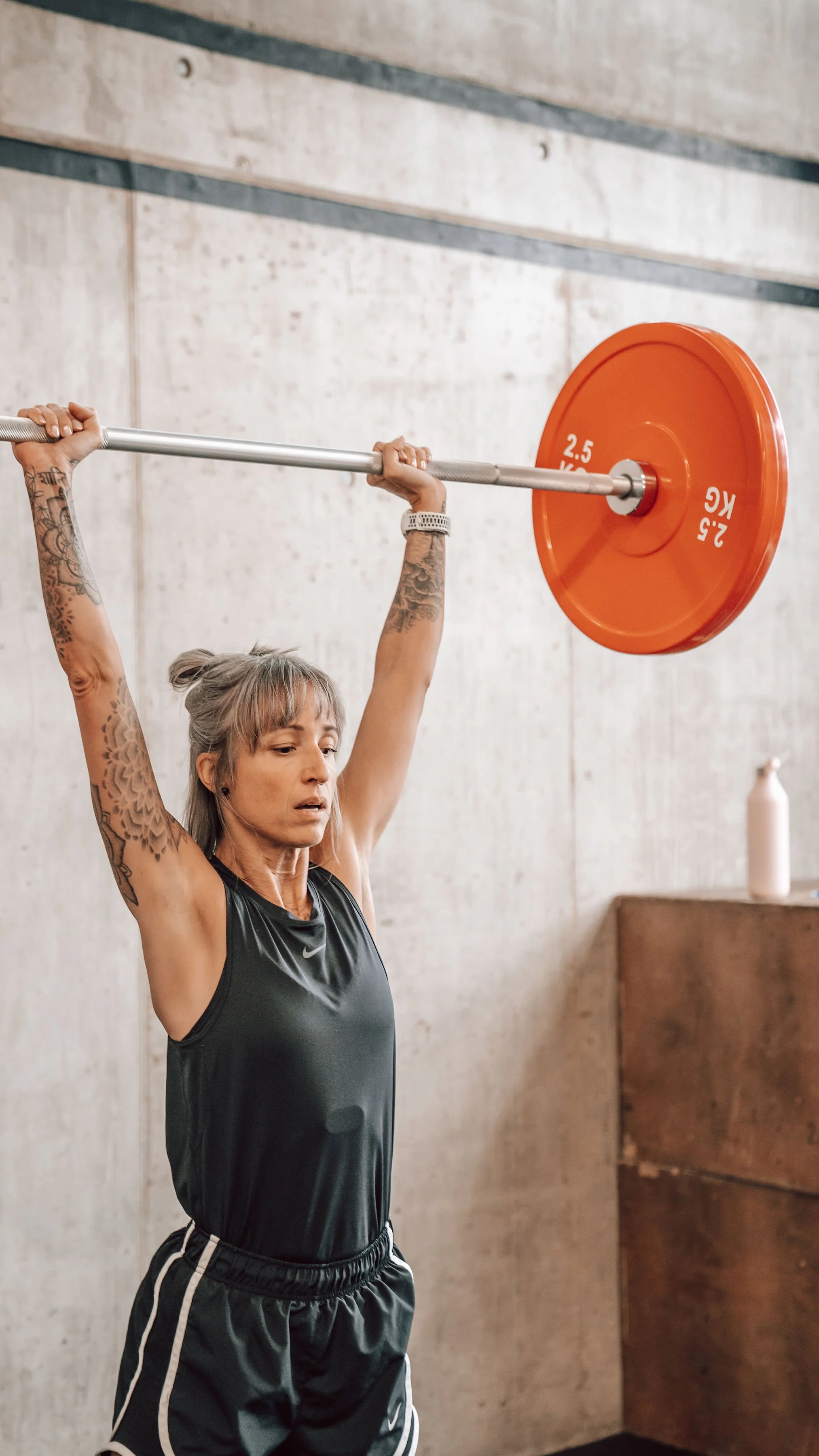 Une femme forte qui souleuve des poids pour faire face à la sarcopenie et battre les symptômes de la menopause
