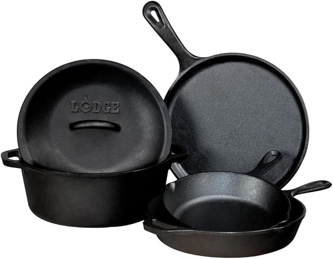 Set of four black cast iron skillets of different sizes, stacked and arranged on a white background.