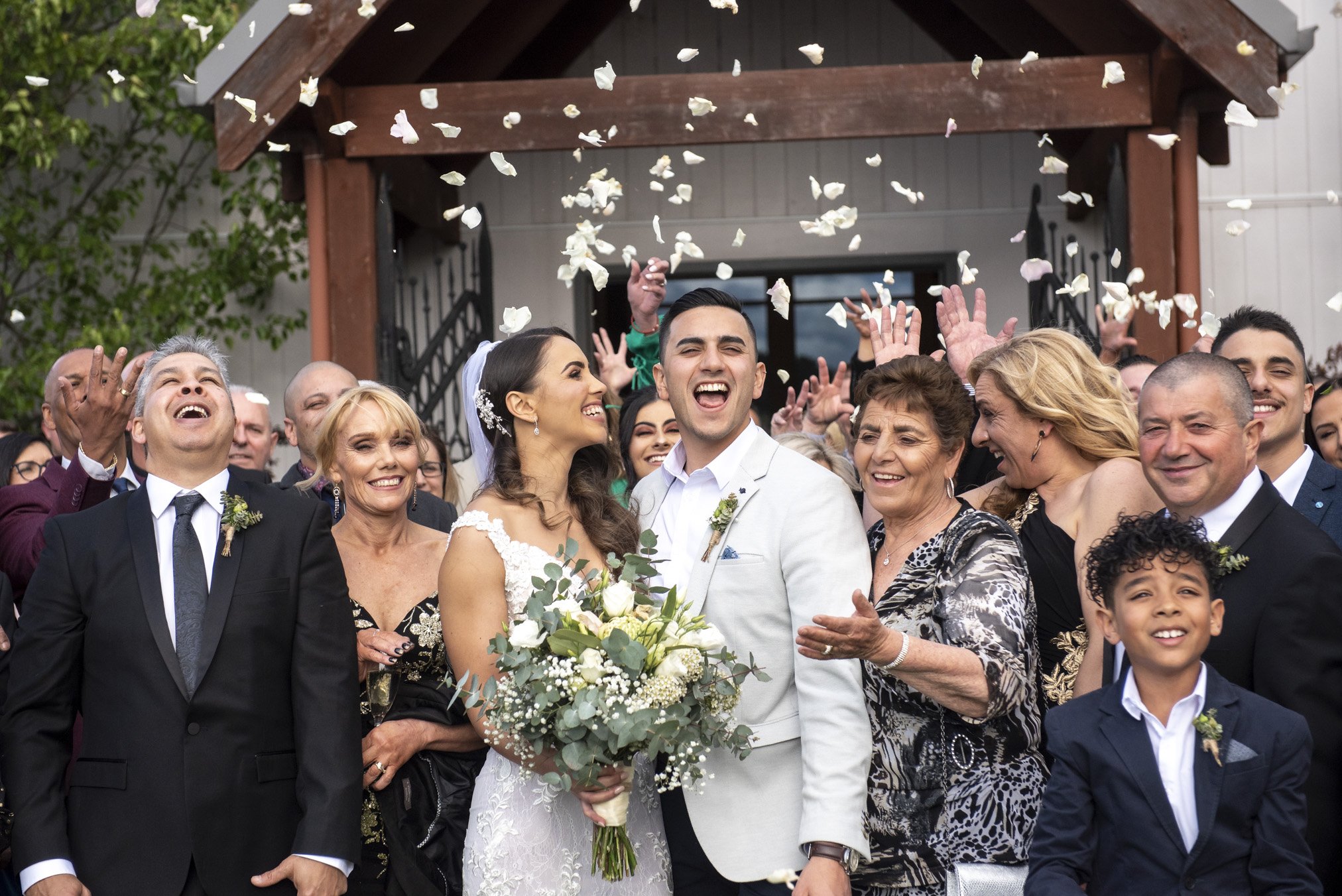 A joyful bride and groom celebrating with family and friends at their wedding, surrounded by confetti.
