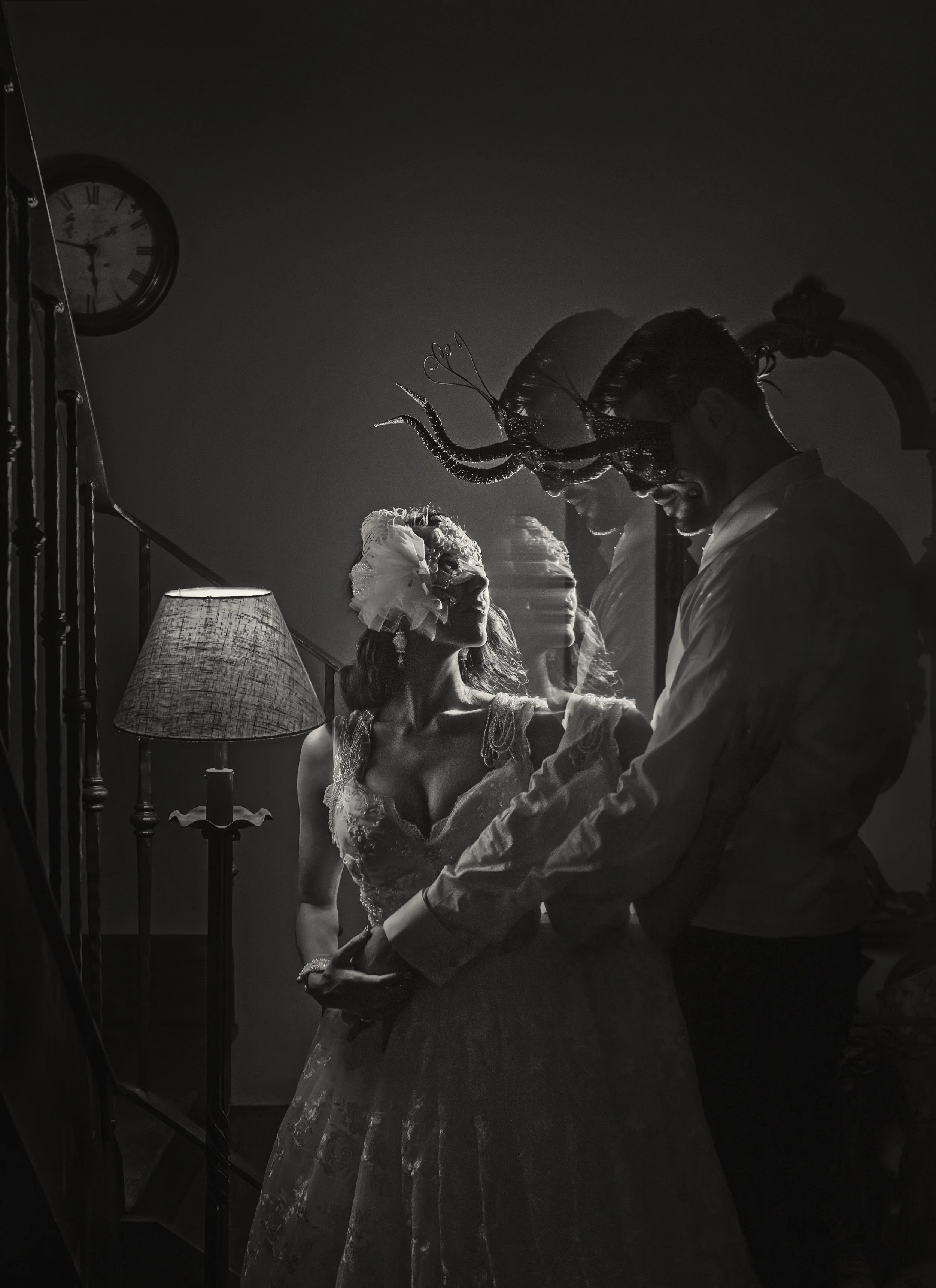 A black and white photo of a couple dancing indoors. The woman wears a dress and headpiece, and the man wears a shirt. There is a lamp, wall clock, and mirror in the background. The image has multiple overlapping exposures creating a ghostly effect.