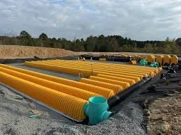 Large yellow industrial pipes with blue caps laid out on the ground in an outdoor construction site.
