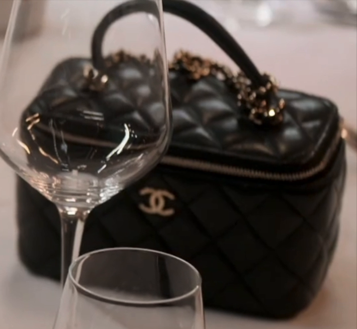 Close-up of Daisy Toye's black Chanel top handle vanity case with gold CC and chain-wrapped handle