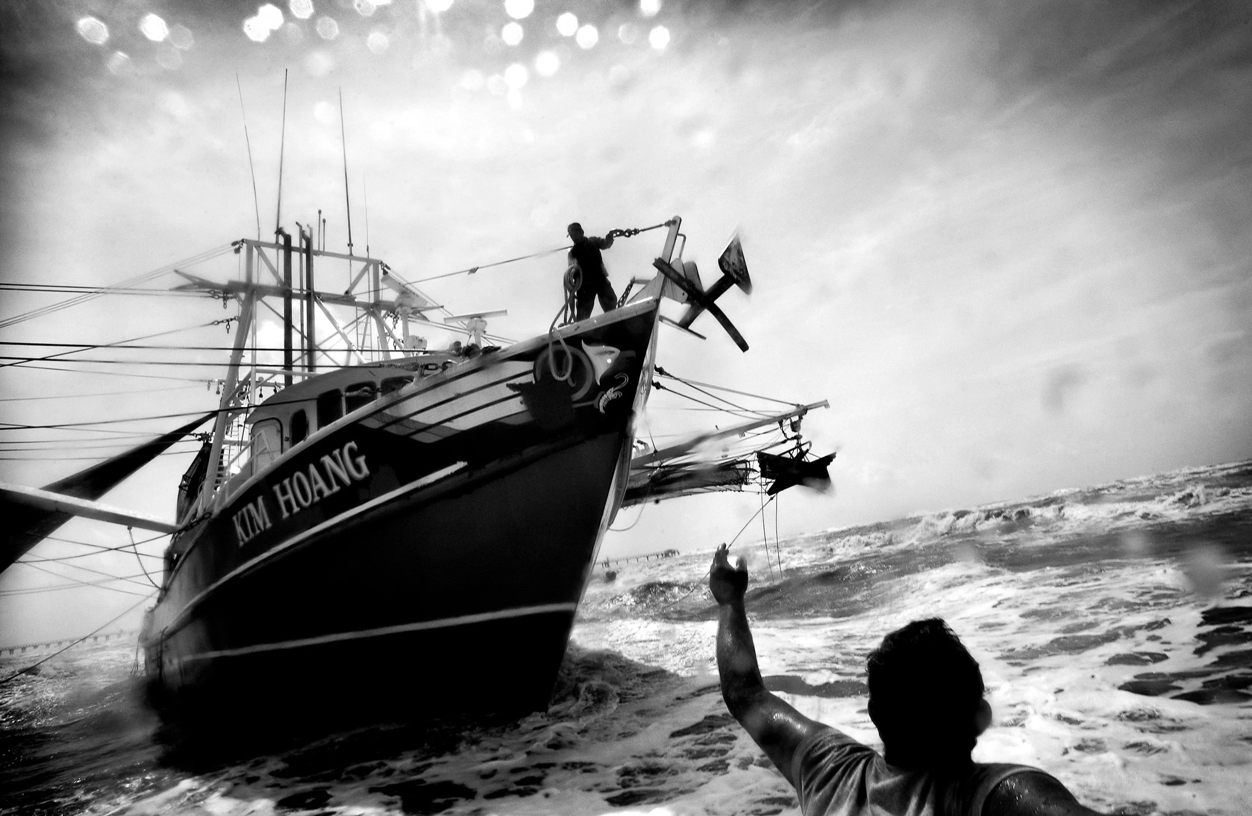 A Texas Gulf Coast shrimper reaches toward the Kim Hoang fishing boat in rough water.