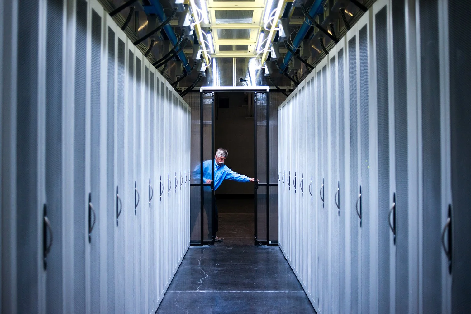 A Digital Realty employee opens a secure door between rows of server cabinets.