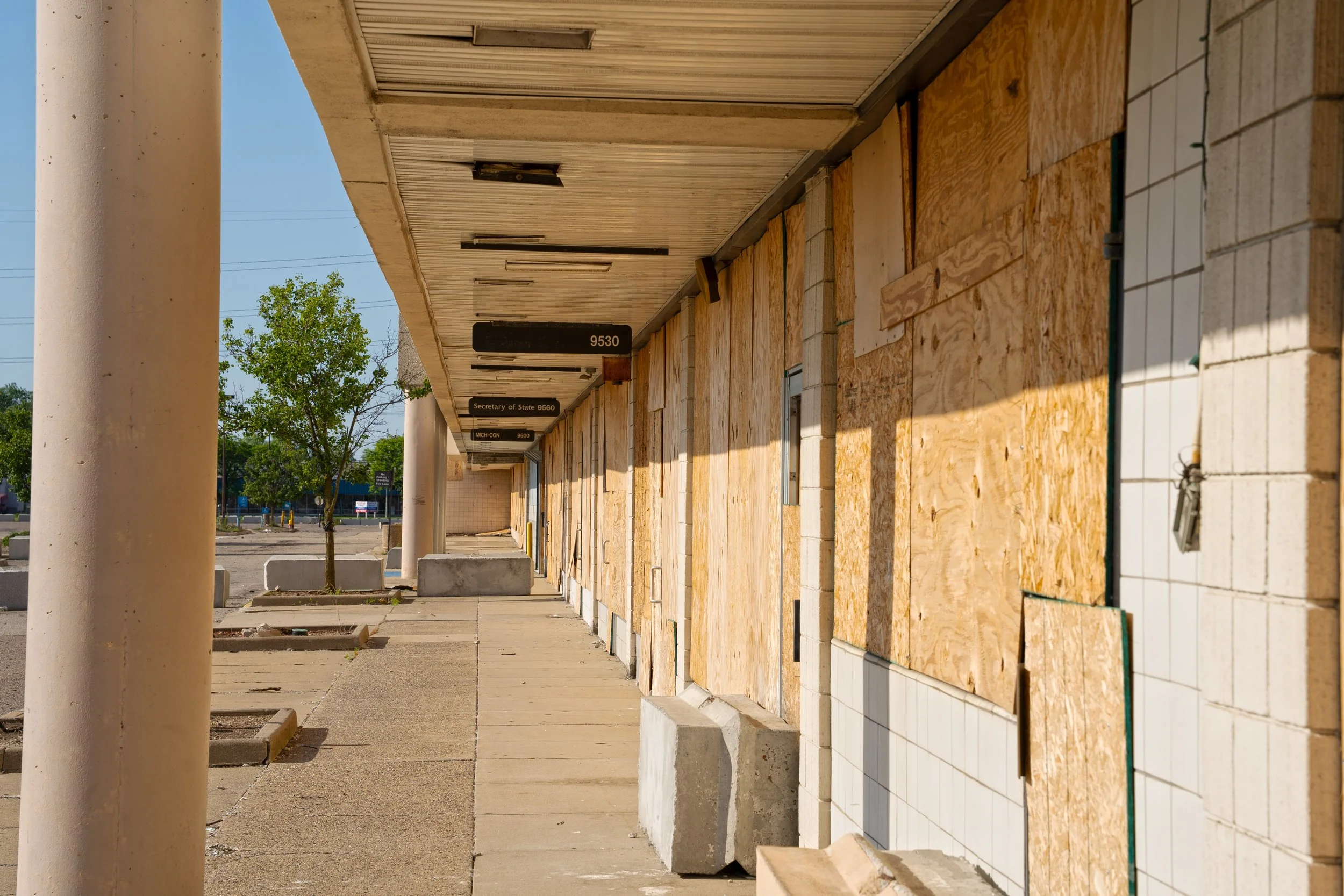 Every store front is abandoned and boarded up, however some signs of former businesses remain 