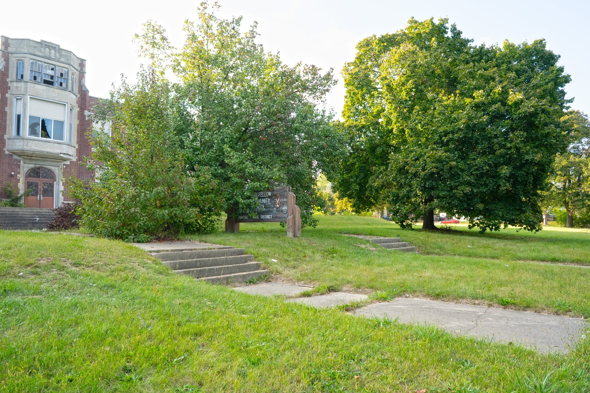A group of trees lines the front lawn of the school