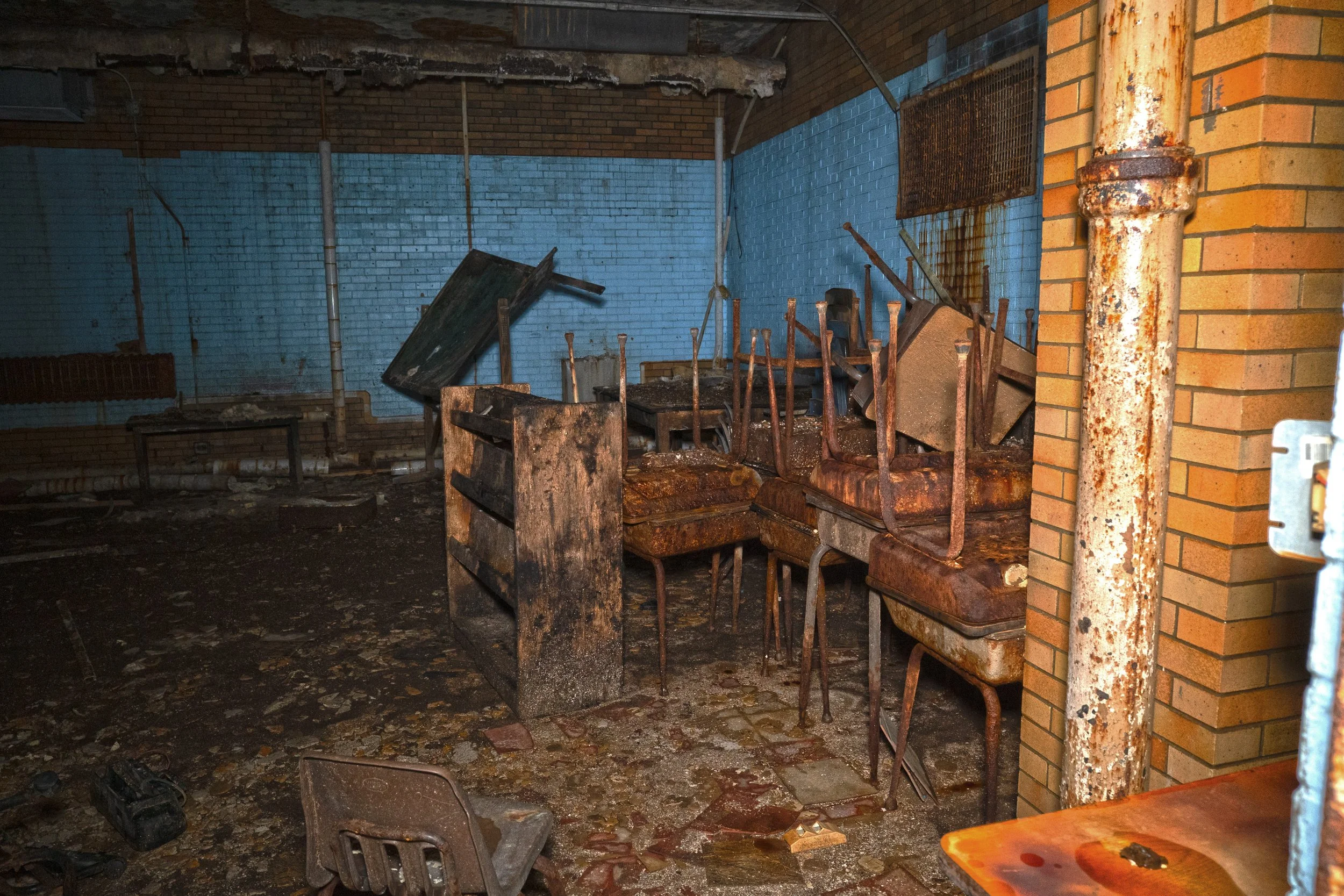 A very poor shape basement classroom desks and chairs have rusted beyond repair