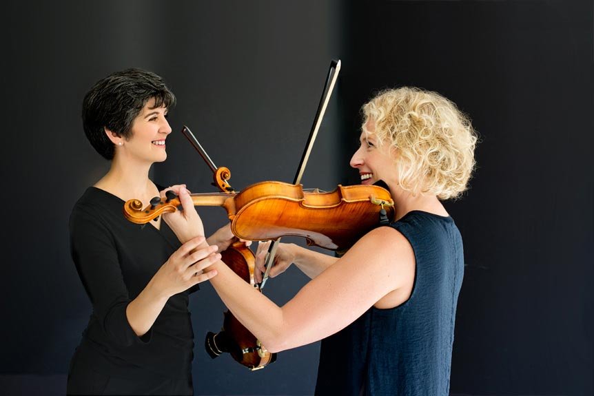 Branding portrait of violin teacher with student practicing her instrument.