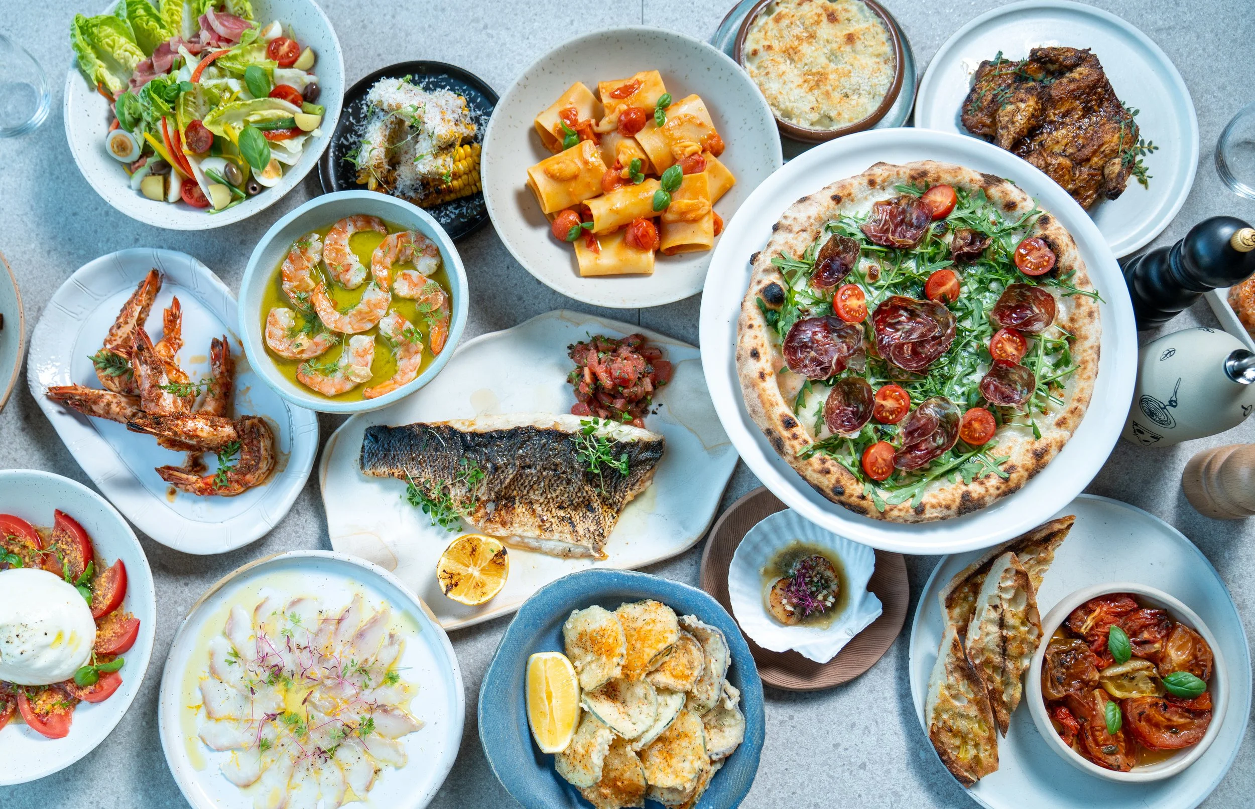 A table set for many — salads, pasta, pizza, the grill, and everything in between.