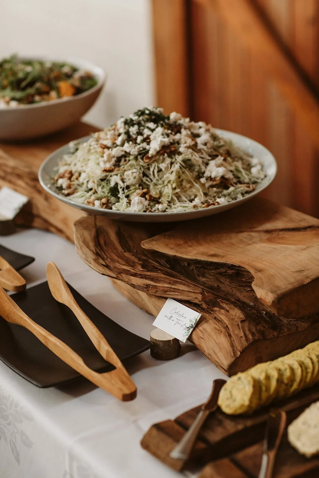 A plate of salad with shredded vegetables, nuts, and cheese on a wooden serving board at a wedding buffet table.