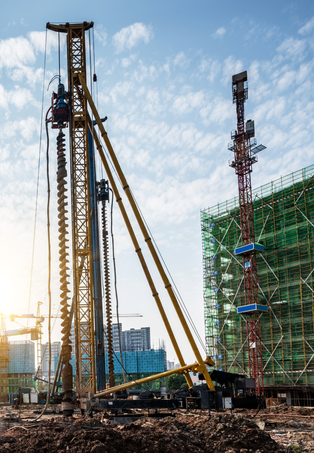 Construction site with two cranes and a building under construction in the background.