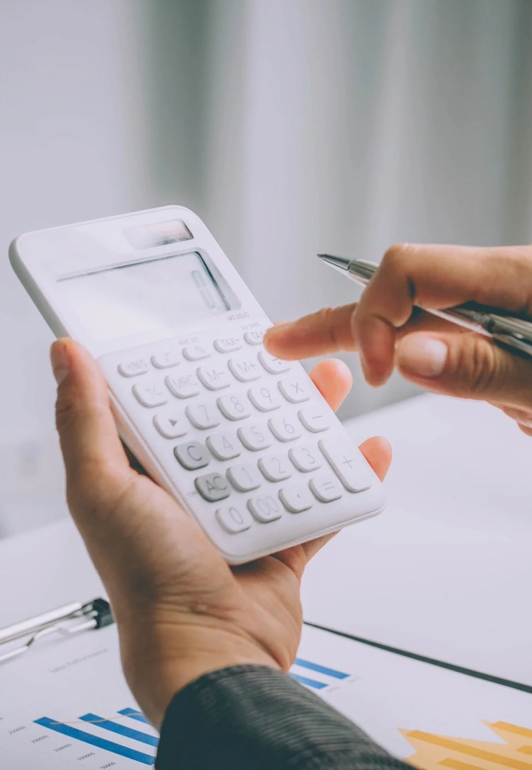 Person holding a calculator and pointing to it with a pen