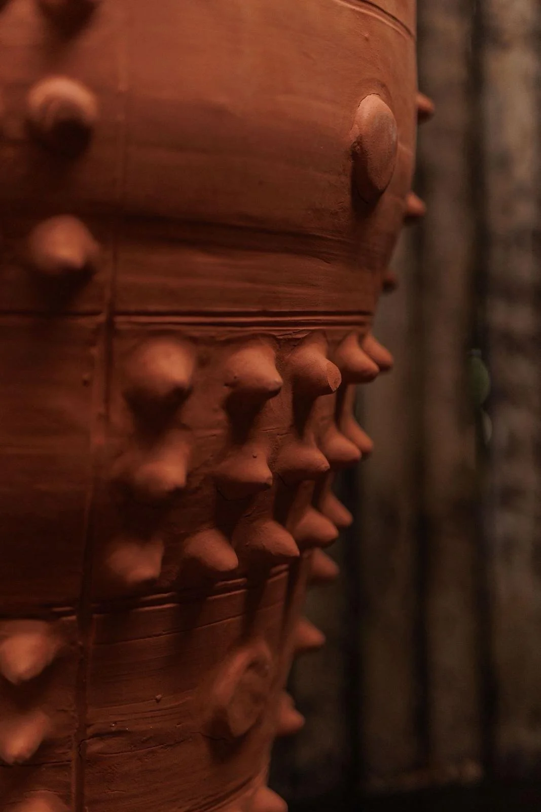 Close-up of a wooden sculpture featuring multiple human faces carved into the surface.