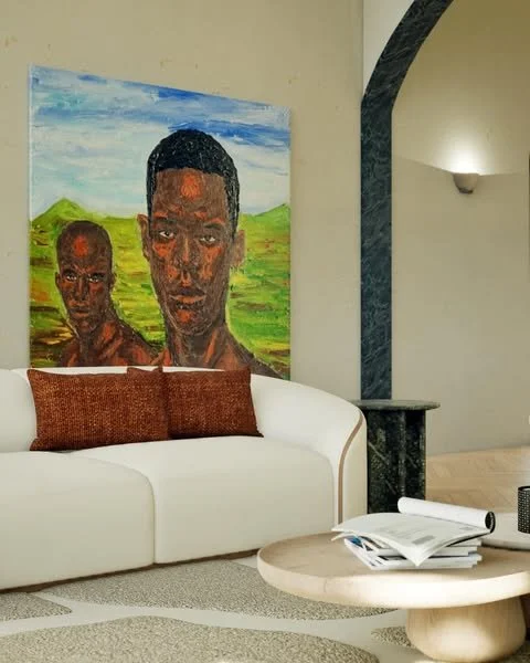 A living room with a white sofa, brown cushions, a circular wooden coffee table with books, a large colorful portrait painting of two people on the wall, and a lamp on a wall in the background.