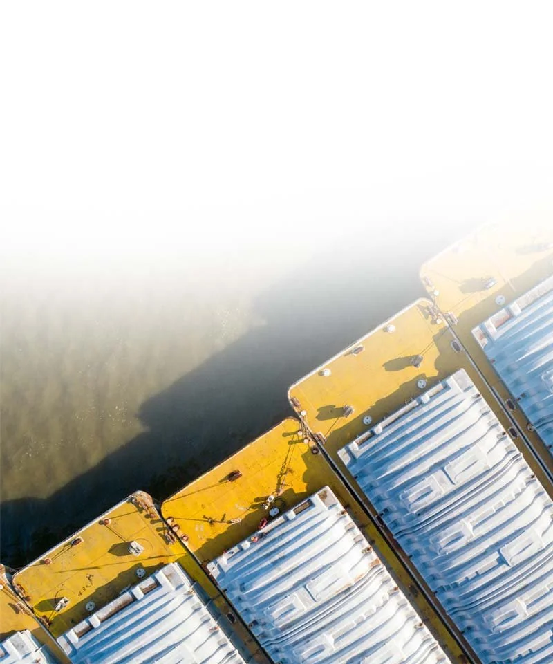 Aerial view of docked boats with yellow and white roofs, casting shadows on the water.