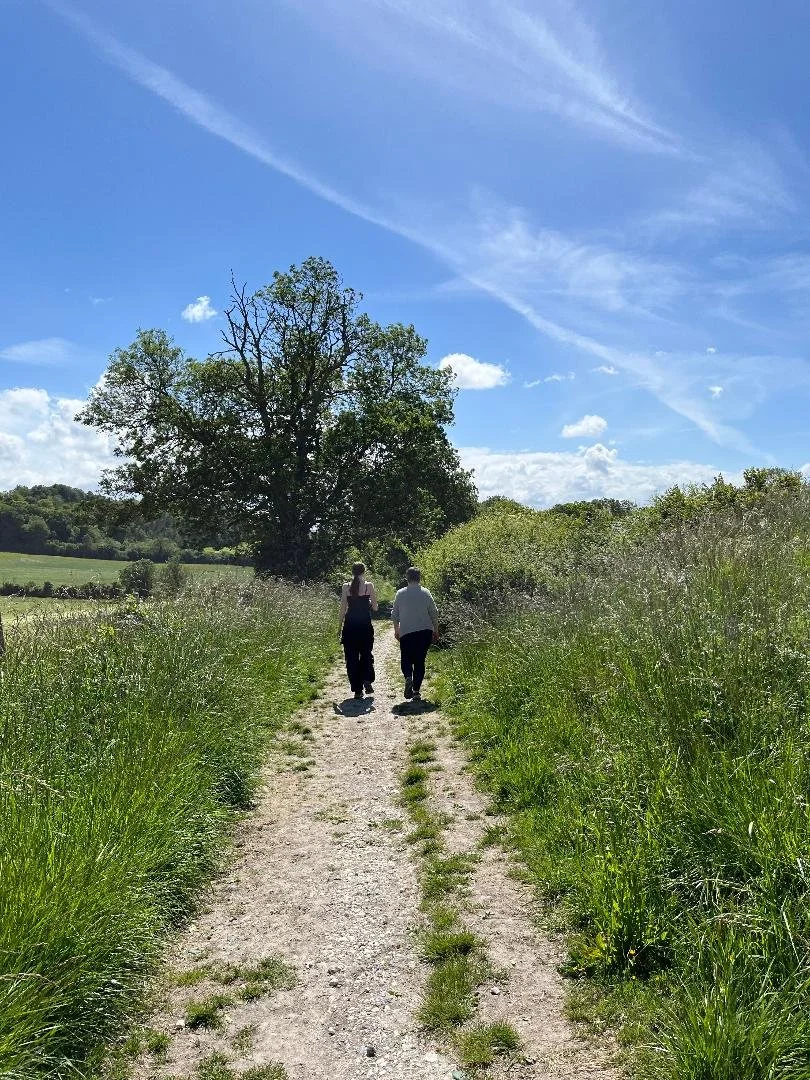 Two people walking side by side on a nature trail, reflecting connection, conversation and emotional wellbeing.